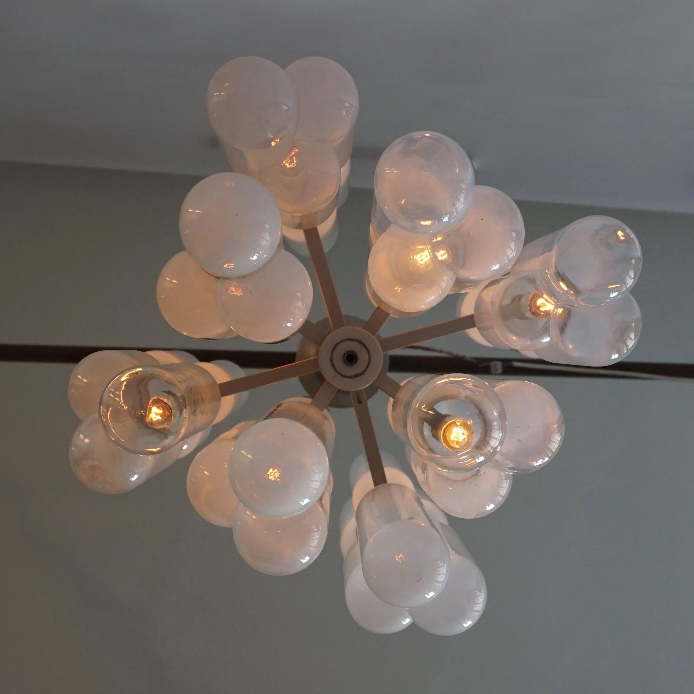 Exceptional chandelier with eight arms carrying three tube handblown glass tubes in opaline white and transparent glass. This creates a wonderful up and down lighter. The brushed aluminium frame has a modernist and stylish appearance neatly dividing