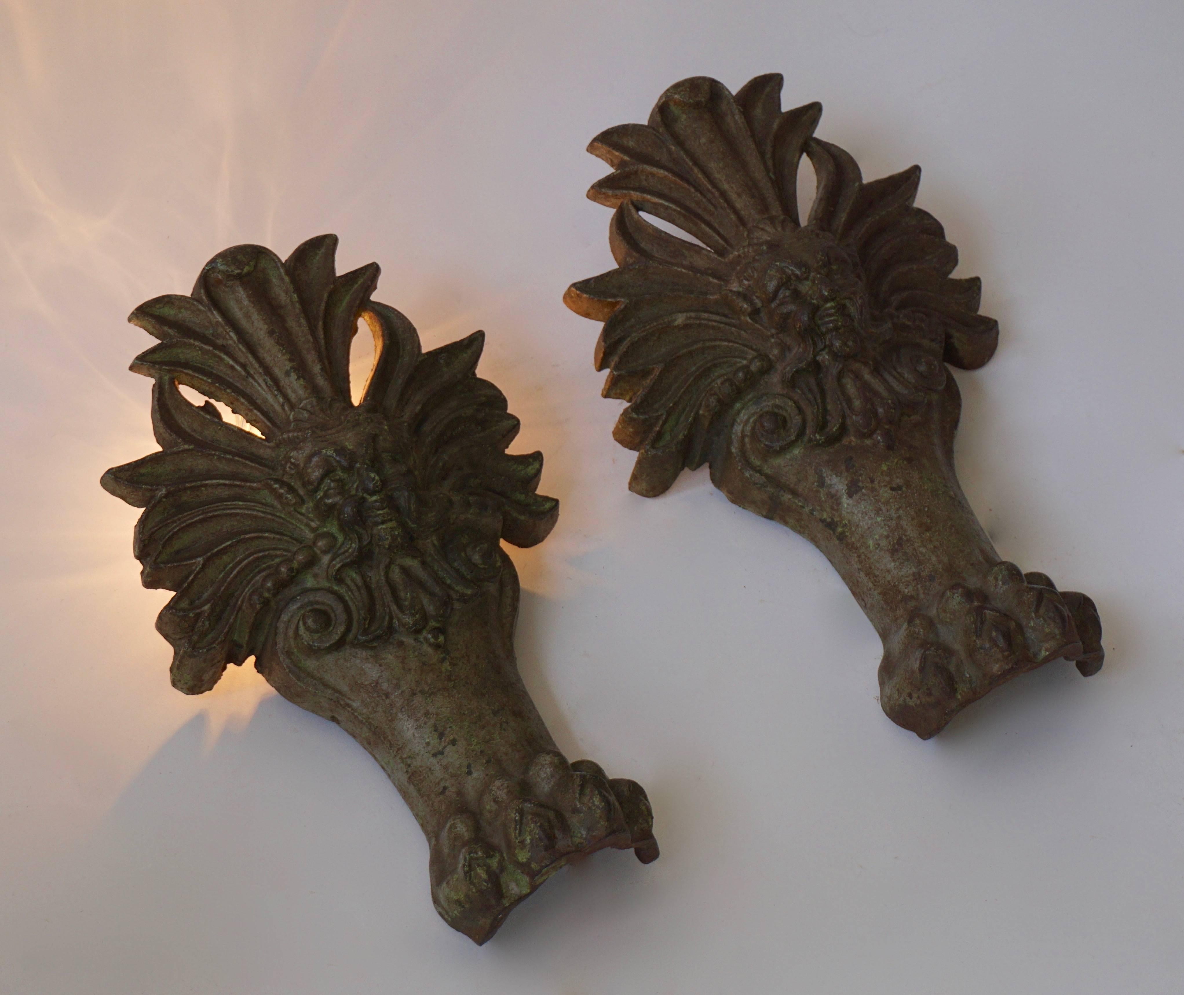 Two cast iron wall lamps in the shape of a man's heads and lion claws.

Measures: 
Height 36 cm.
One E14 bulb.
