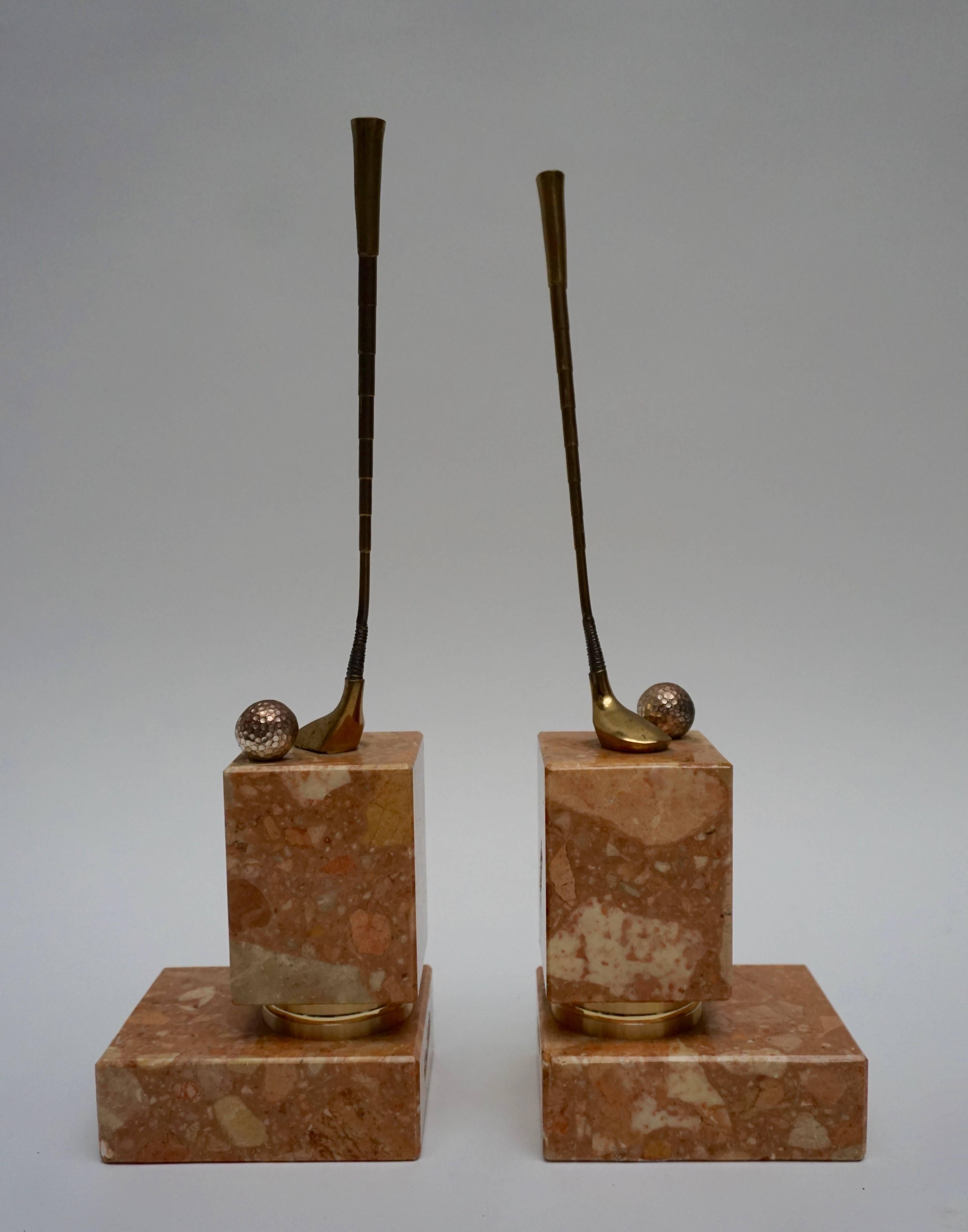 A pair of red Italian Breccia marble, gilt, silvered and brown patinated bronze bookends, representing the sport of golf.
On top of each one a dark patinated and gilt bronze golfstick together with a silvered bronze golf ball. 
Art Deco style and