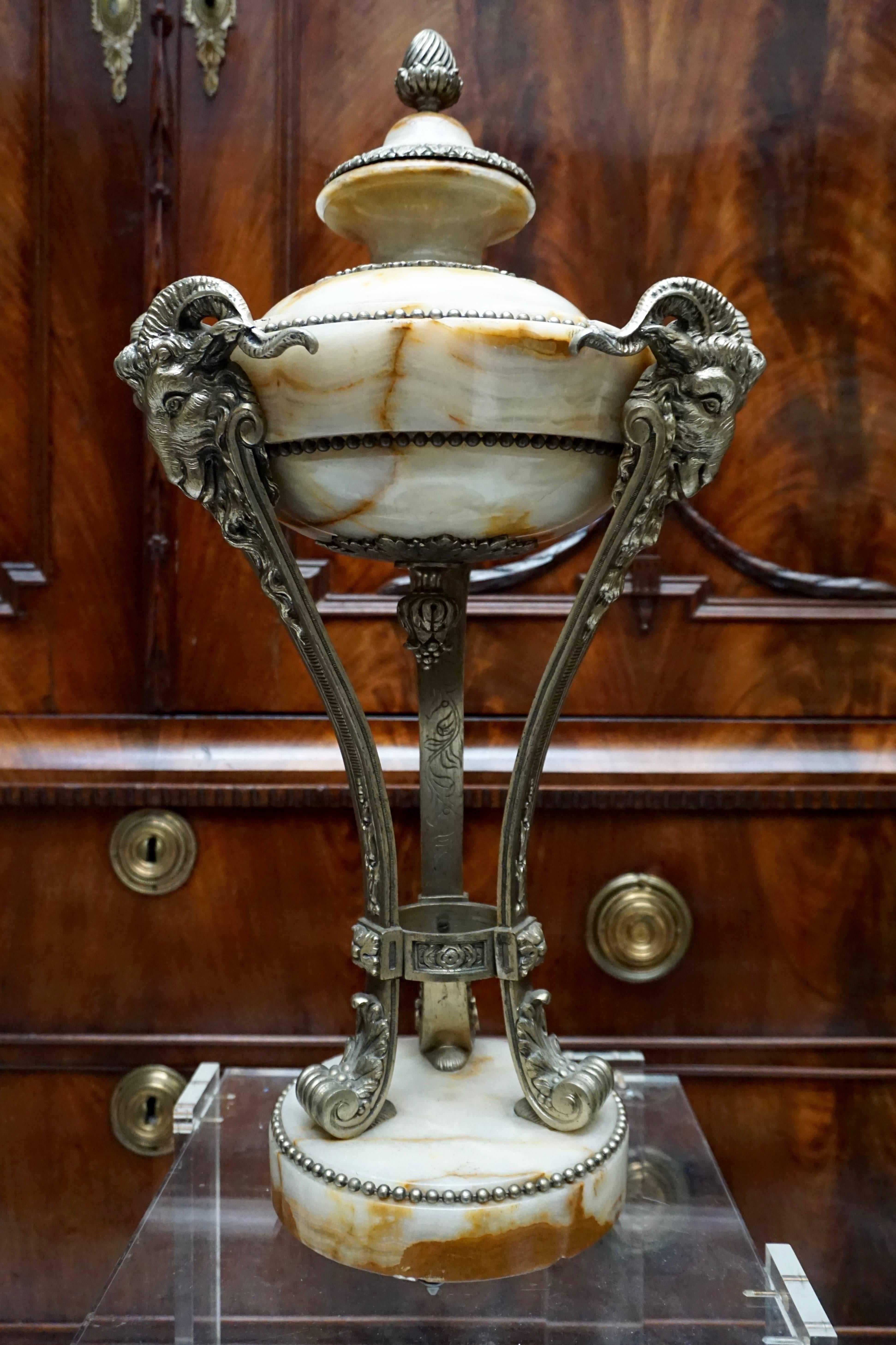 A good pair of antique marble cassolette.

A nice pair of onyx and silvered bronze ornamental vases in the Robert Adam style.
The three feet resting on circular onyx bases and decorated with ram's heads, topped by pinecone finials.
Early 20th