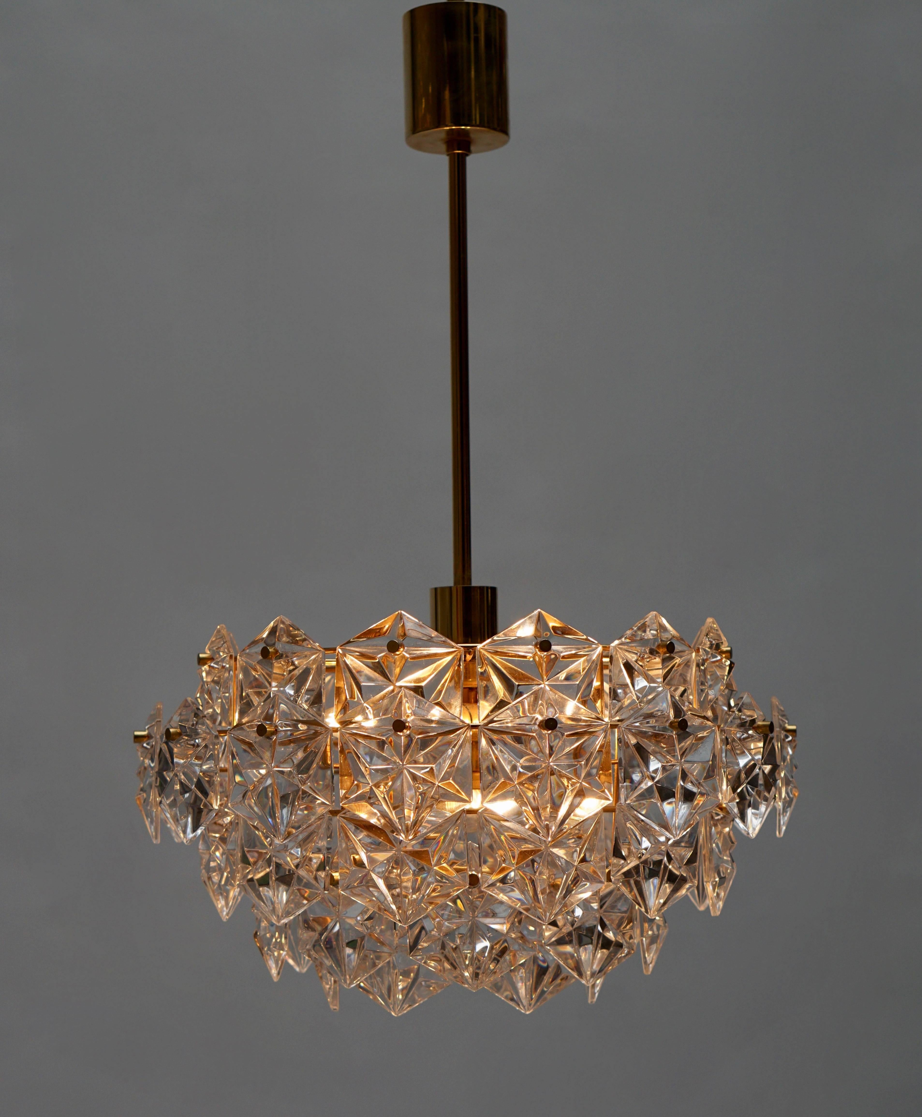 This Mid-Century Modern chandelier by Kinkeldey of Germany very much evokes the modern version of the Hollywood-Regency style with its 24-karat gold-plated frame which supports five-tiers of clear flat-backed, hexagon shaped, multifaceted crystal