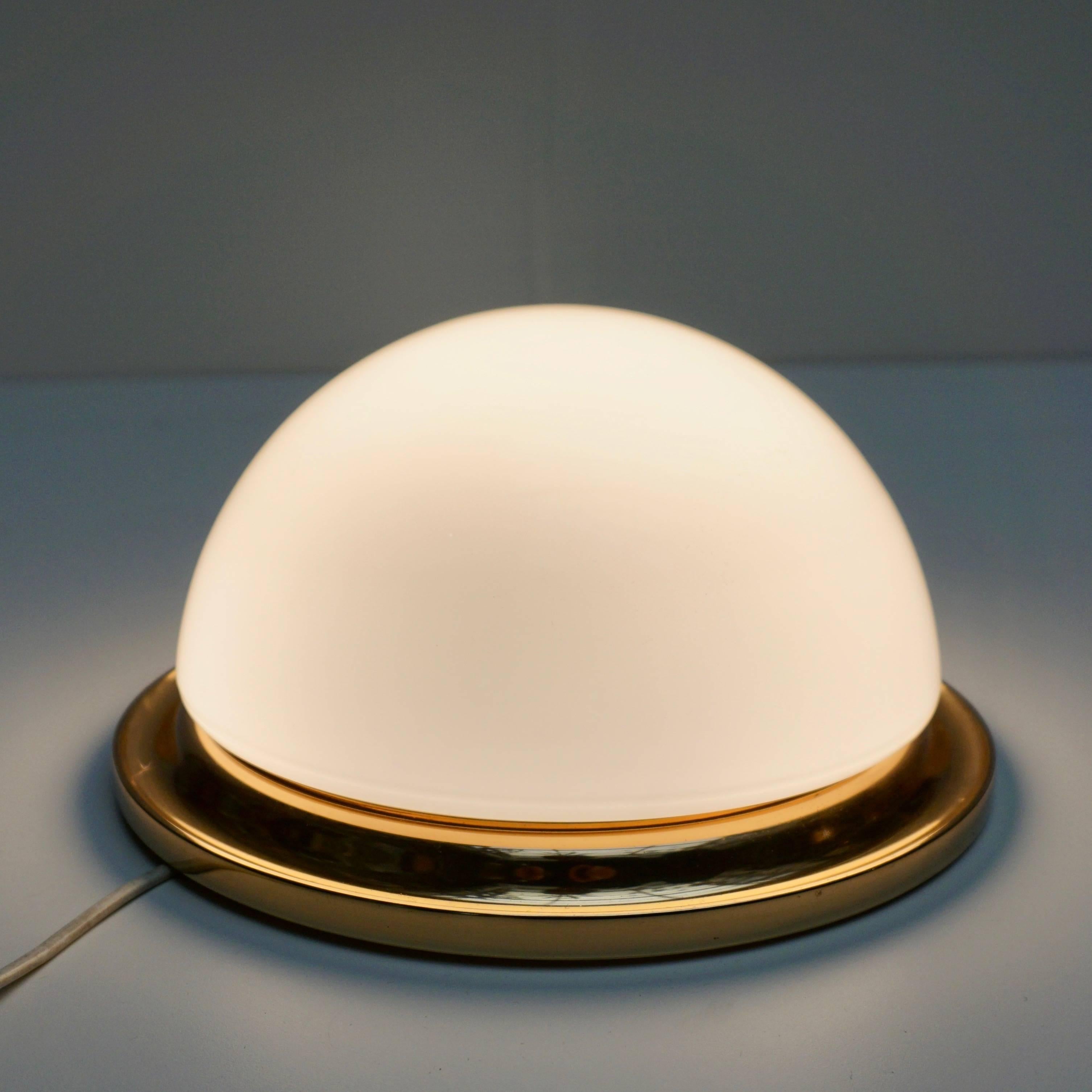 Five Minimalist polished brass and glass flush mounts by Limburg.
The polished brass armature supports the glass dome and is illuminated by one light sources and each socket has a 60 watt maximum.

Materials: White opal half round crystal glass