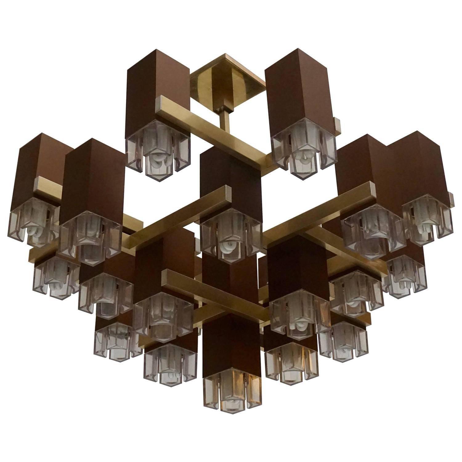 Pristine Sciolari 20 cubic lacquered brass chandelier, 1970s, Italia.
Prime quality material, solid conception and construction, fine assembly and craftsmanship.
A pull down and push up mechanism move the acrylic lens for easy bulbs
