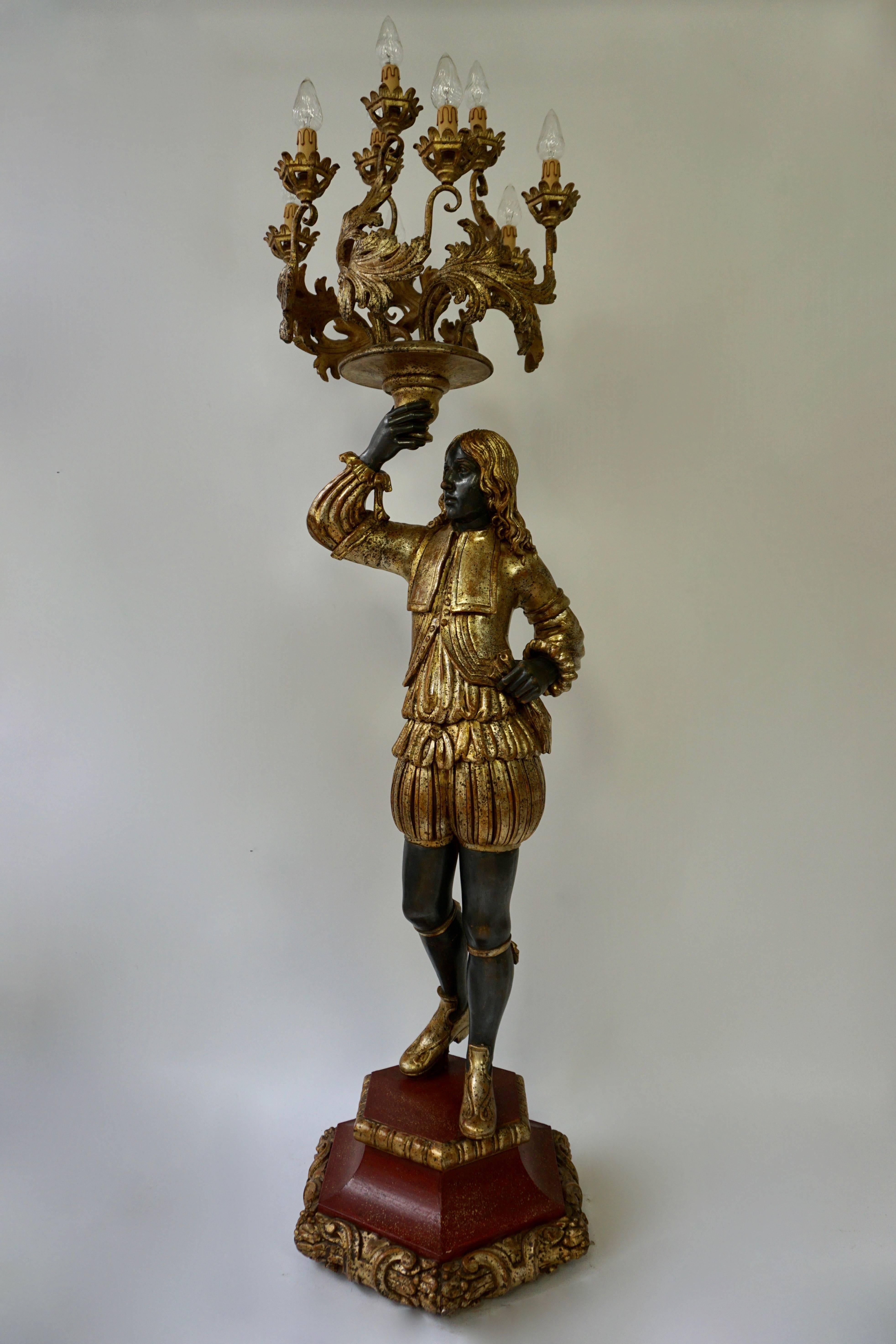 This is an exquisite decorative Venetian style candelabra floor lamp 

The figure are on decorative gilded wooden stand and holds a large gilded candelabra above it's head with nine candle light bulbs.

Dimensions in cm:
Height 194 cm x width