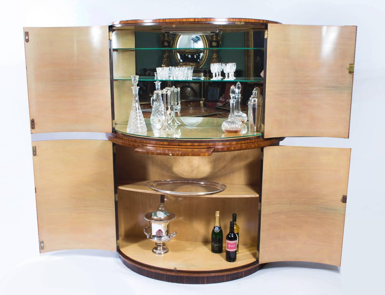 This is a fantastic antique demilune Art Deco burr walnut cocktail cabinet, circa 1930 in date and in the manner of Epstein.

This beautiful cabinet's upper part comprises a pair of glass shelves over a slide with a fitted maple and mirrored