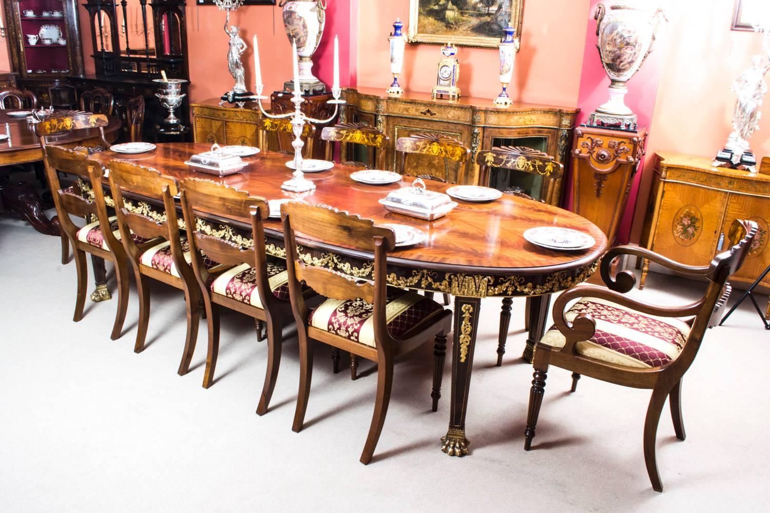 This is a very impressive and rare antique extending dining table in the neoclassical style, circa 1920 in date, with a matching set of ten burr walnut and inlaid dining chairs.

The table is made of flame mahogany and is decorated with a