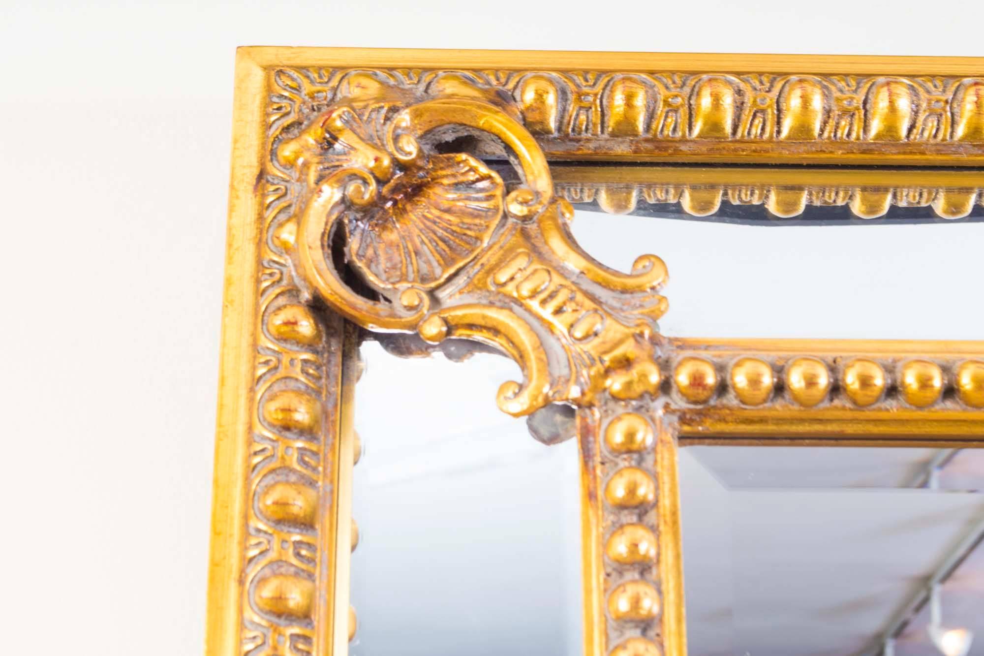 This is a beautiful rectangular gilded mirror dating from the last quarter of the 20th century.

The mirror is in French style with raised central looking glass, flanked by a border of angled glass sides, making a 'cushion' shape. 

The frame is