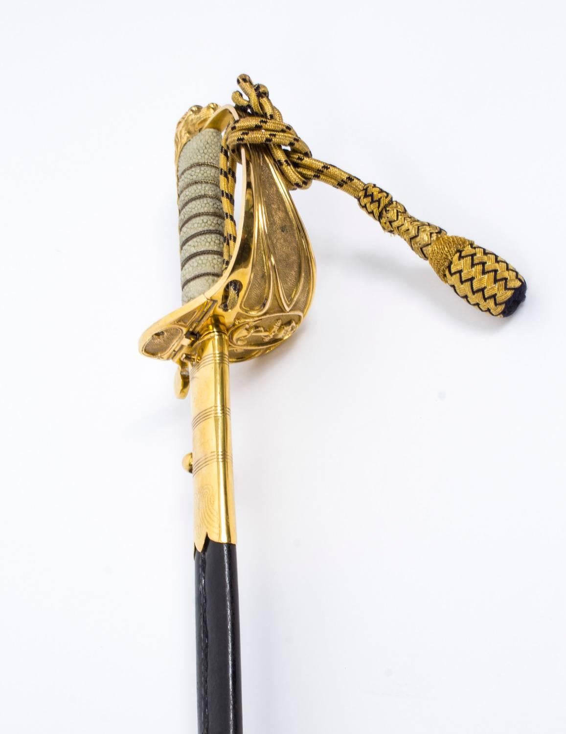 This is a stunning Royal Naval Officer's sword and scabbard by Gieves Ltd, dating from the early 20th century.

With etched blade, gilt hilt and wire bound ray skin covered grip, cords and sword knot. The beautiful gilt brass-mounted leather