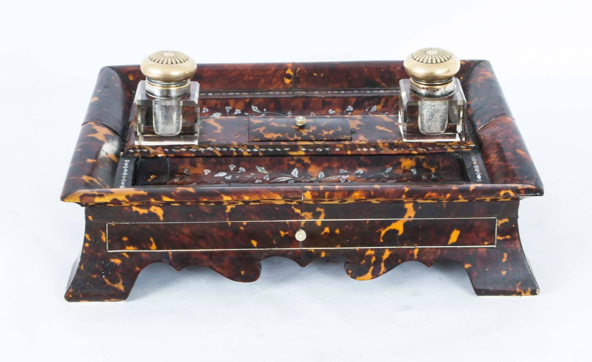 This is a lovely antique French mother-of-pearl marquetry and red Boulle encrier, or inkstand, circa 1830 in date.

The encrier comprises two glass inkwells and a lidded stamp box with a sunken well. It has exquisite inlaid mother-of-pearl Boulle