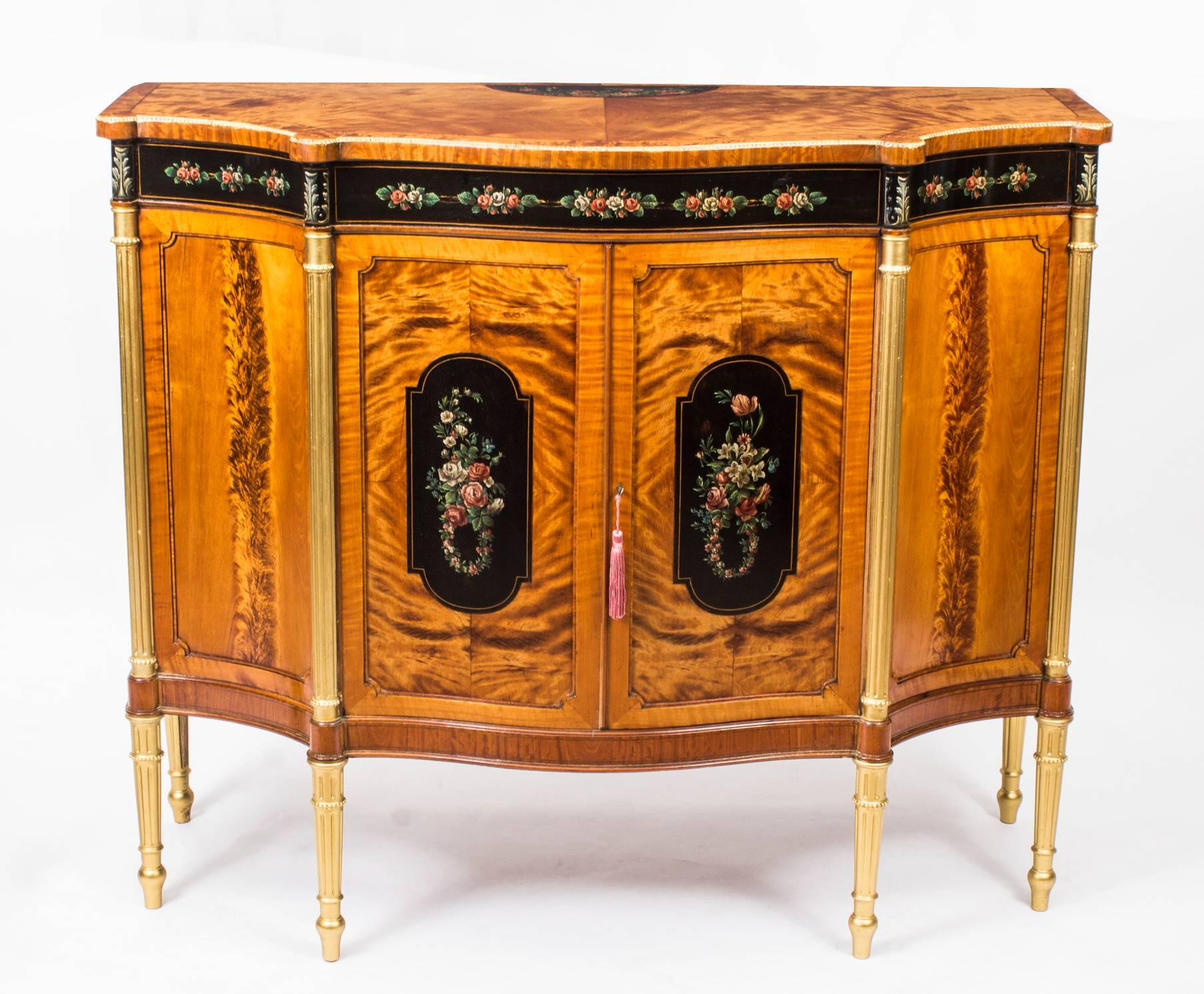 A stunning English Edwardian hand-painted and inlaid shaped serpentine satinwood side cabinet, circa 1900 in date and of the very highest quality.

With exquisite hand-painted floral decoration on an ebonised ground, in the manner of Angelica