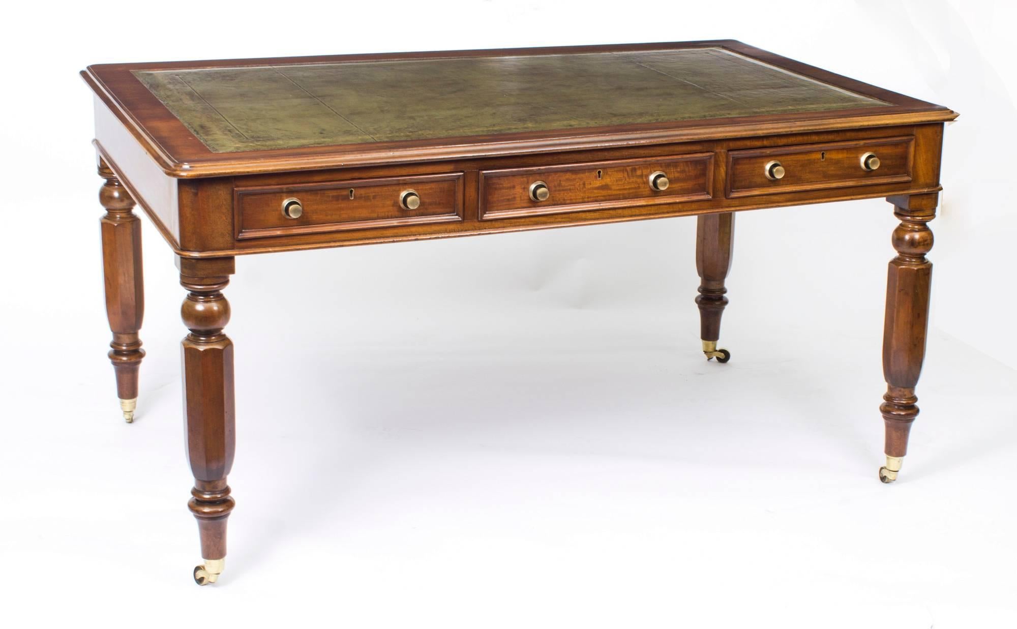 This is a gorgeous antique William IV partner's library table, circa 1840 in date.

It is crafted from beautiful solid mahogany and features a striking faded green and gold tooled inset leather top. It is raised on four faceted legs that terminate