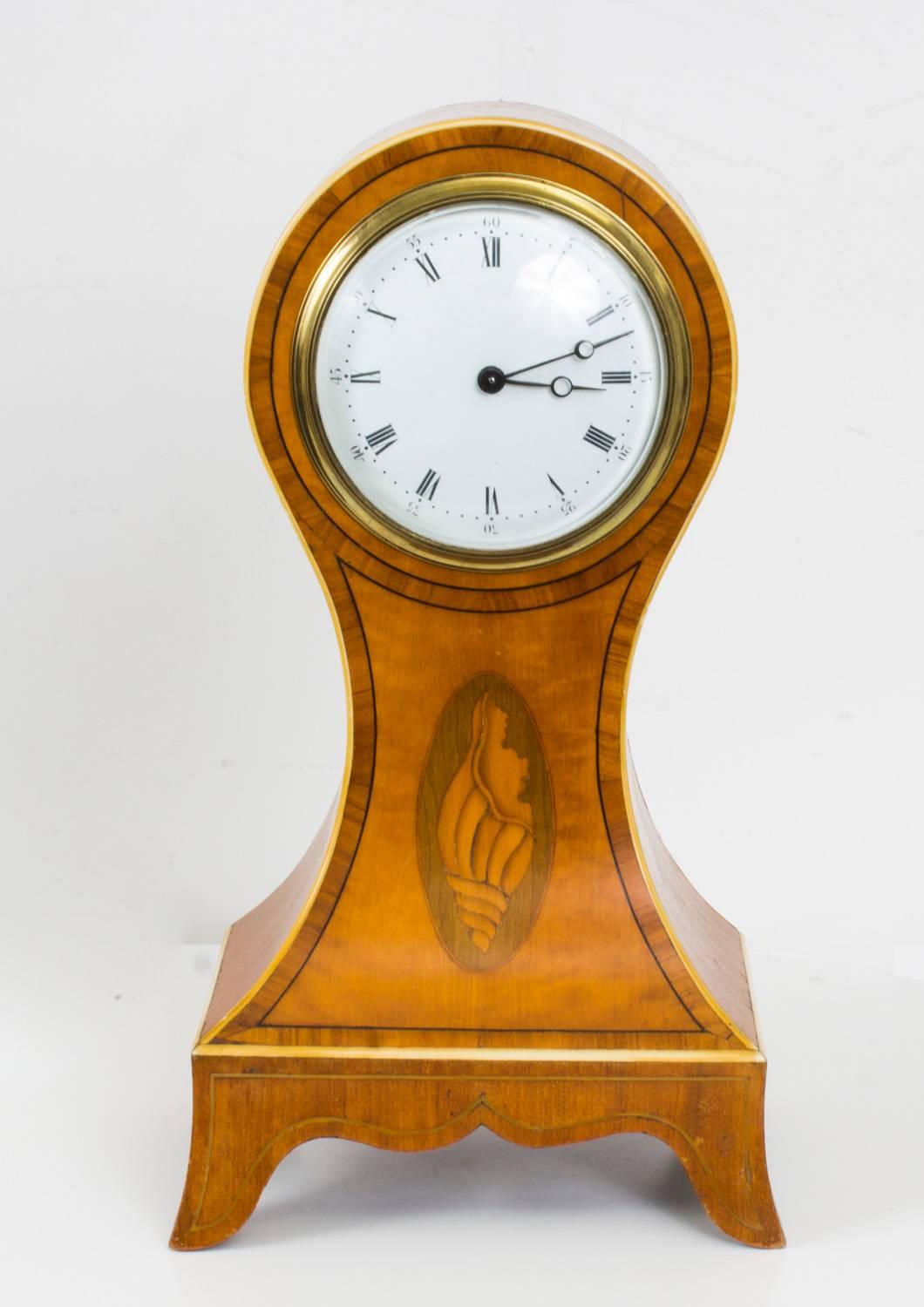This is a pretty antique Edwardian inlaid satinwood mantel clock, circa 1900 in date, it comes complete with the original winding key.

It has a beautiful beautiful balloon shaped case with ebony string inlay and conch shell detail, with enamelled