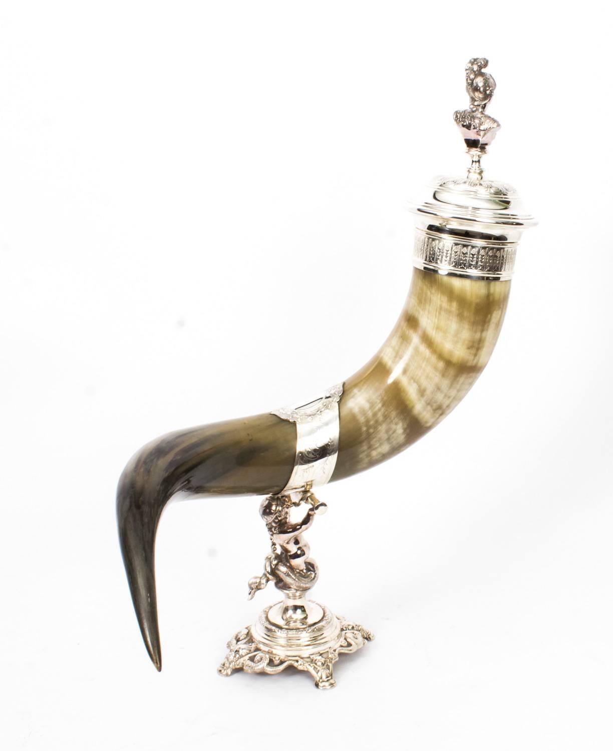 This is a large and decorative antique silver plated horn cornucopia, circa 1890 in date.

The horn is mounted on a detachable silver plated base that rests on a delightful cherub riding a dolphin.

The mounts and plaques have engraved and