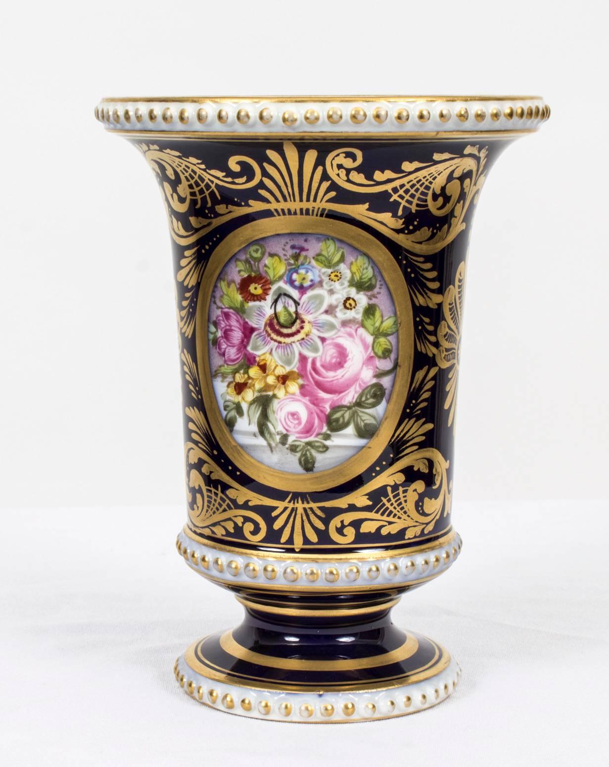 This is a truly superb pair of hand-painted Derby porcelain spill vases, circa 1900 in date.

Beautifully hand-painted with oval panels of flowers on a Royal Blue ground with exquisite gilded decoration and bearing the red painted Derby
