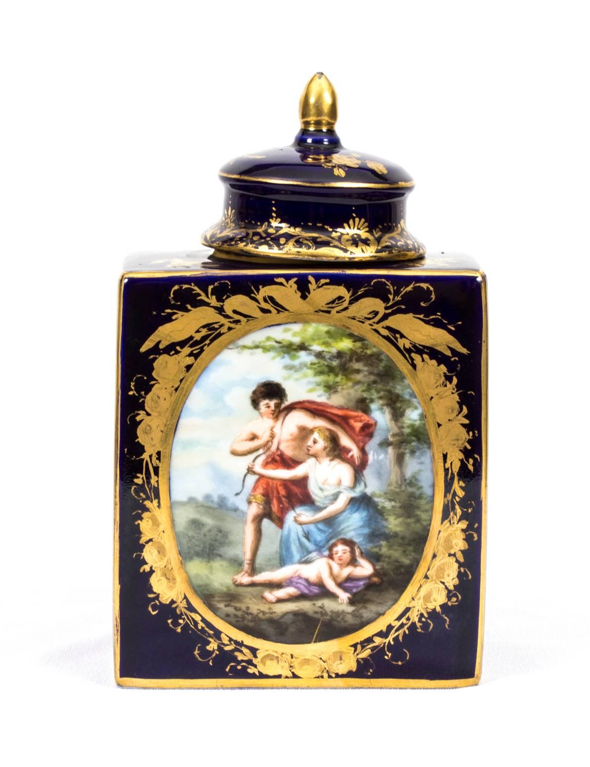 This is a delightful antique Vienna porcelain tea cannister and cover, circa 1900 in date.

It is beautifully painted with an oval gilt framed classical scene on one side, and a mother and child on the other, bearing the printed blue