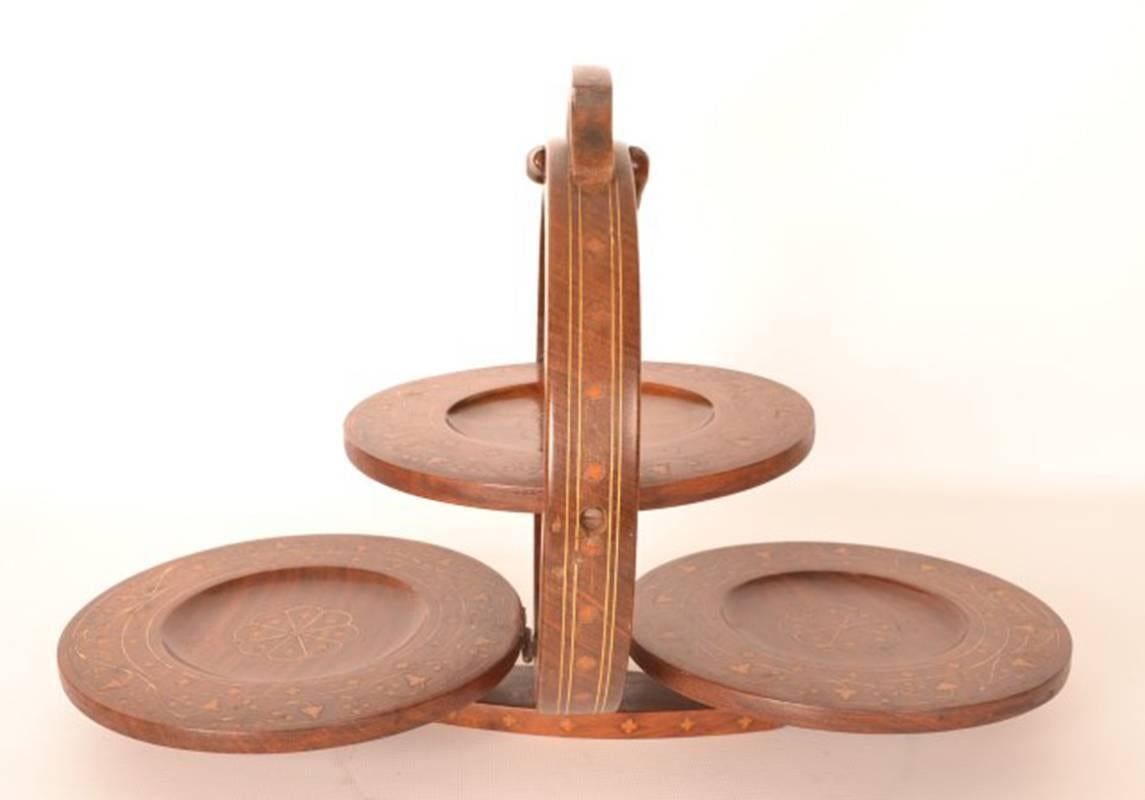 This is a beautiful antique Edwardian three tier folding mahogany table cake stand, circa 1900.

The stand features delicate brass inlay.

The stand comes especially handy while serving an afternoon tea.

Add a little bit of style to your