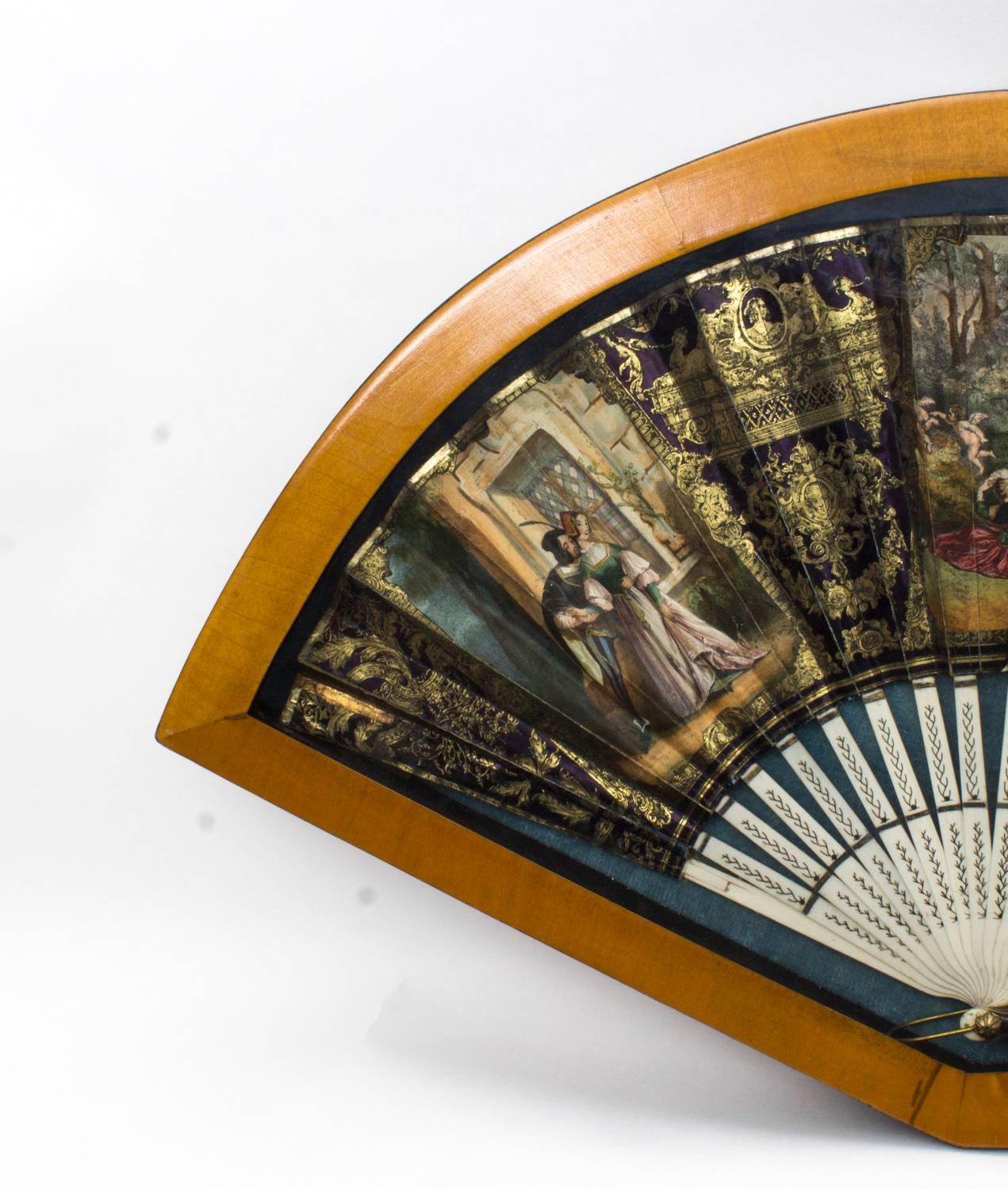 This is a beautiful decorative French mother-of-pearl fan set in a satinwood cased frame, circa 1880 in date.

The fan is made from vellum and is beautifully hand-painted and gilded with three scenes of lovers, on richly gilt shaped and pierced