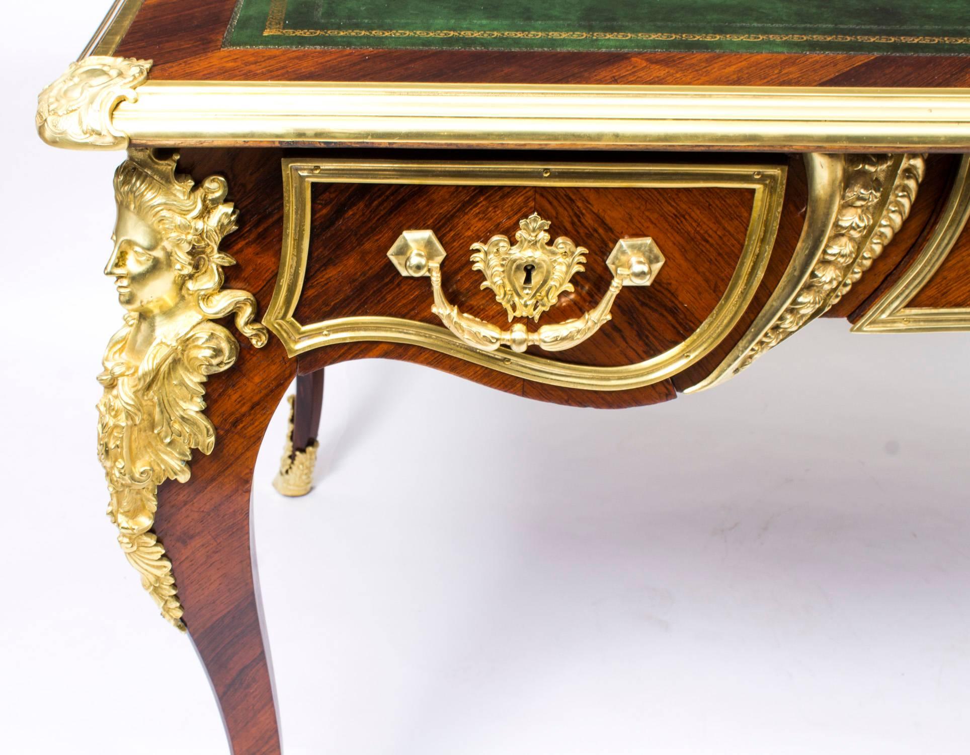 This is a gorgeous antique French kingwood Louis revival bureau plat with highly decorative ormolu mounts, circa 1860 in date.

The rectangular top with with gilt bronze border, raised corner cartouches and a gold tooled green leather inset
