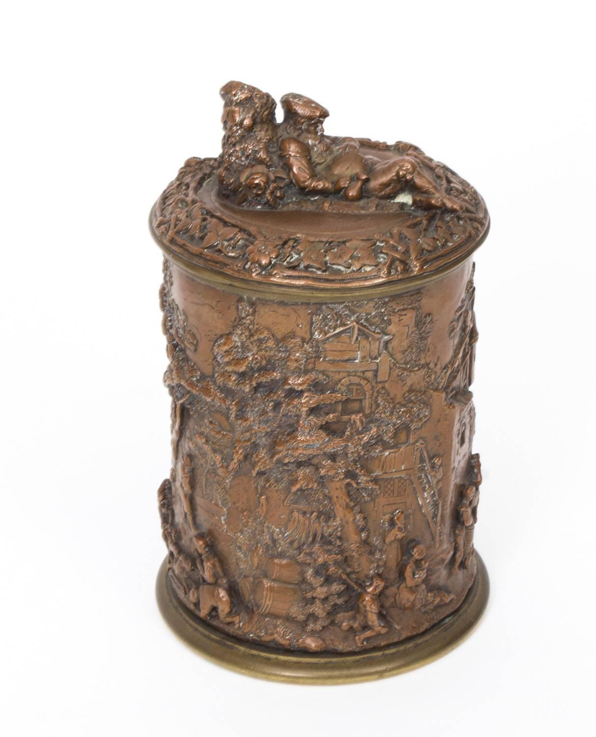 A quality antique copper and bronze cylindrical tobacco jar and lid superbly decorated in relief with stunning Bacchanalian scenes, circa 1860 in date.

It features relief scenes of medieval revellers in a very detailed dramatic landscape with a