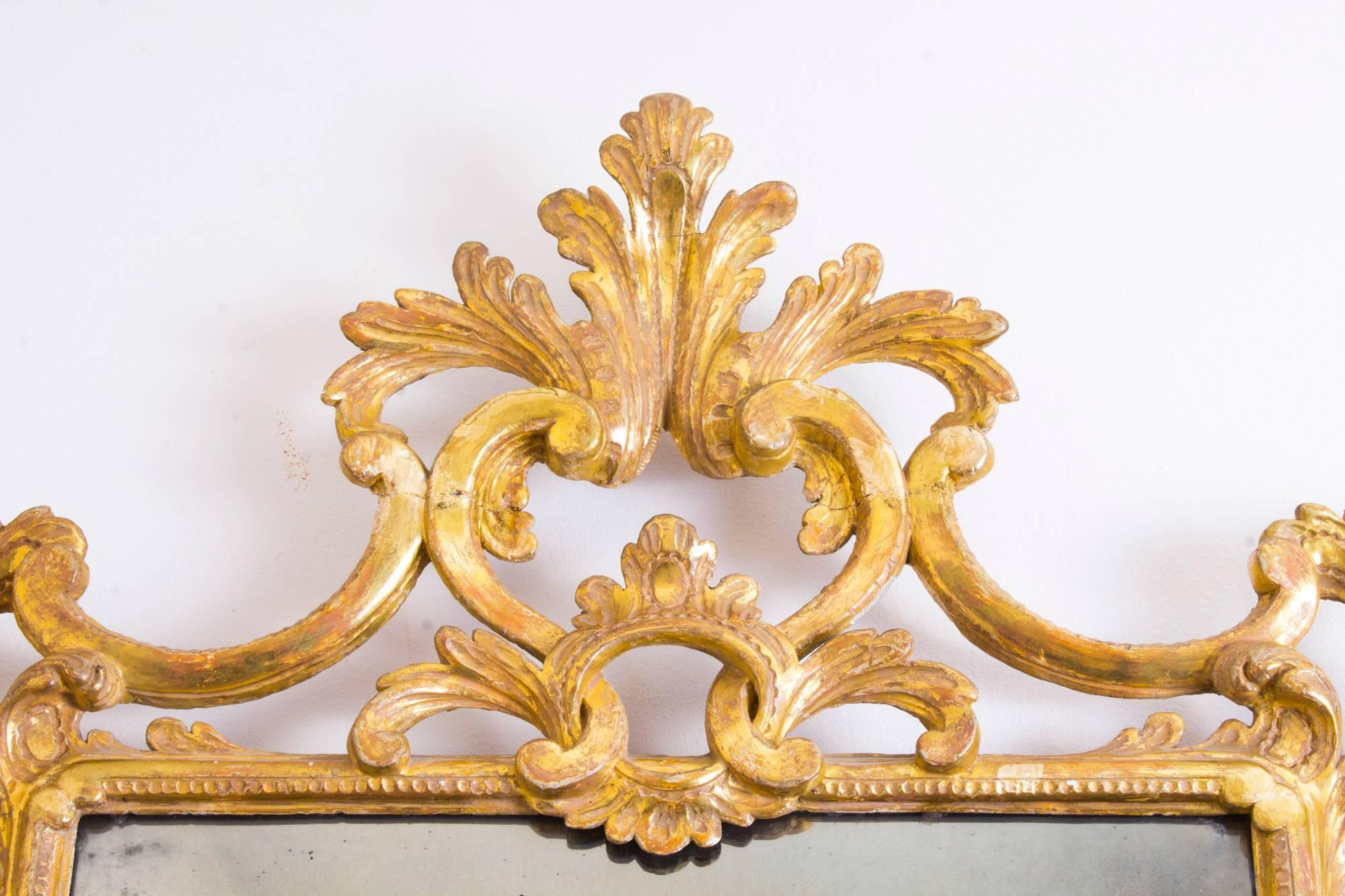 This is a superb antique Italian Florentine carved giltwood mirror, circa 1870 in date.

The rectangular original mirror plate is within a boldly-carved and pierced scrolling foliate frame within a beaded border. 

This is a very decorative item