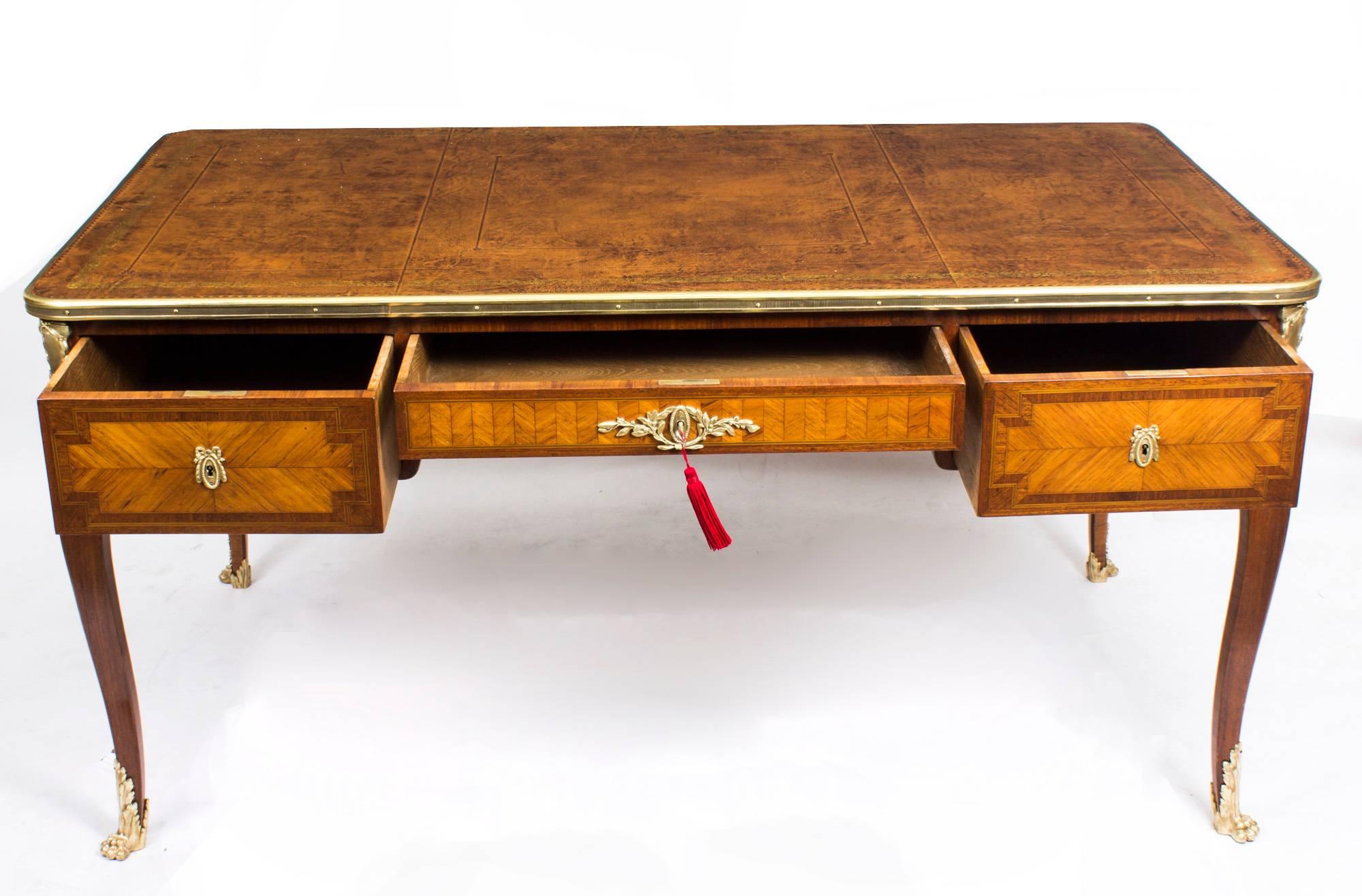 This is a elegant antique French walnut bureau plat with decorative ormolu mounts, circa 1840 in date.

The rectangular top with a beautiful gilt bronze border, raised corner cartouches and a brown leather and gold tooled inset writing surface. It