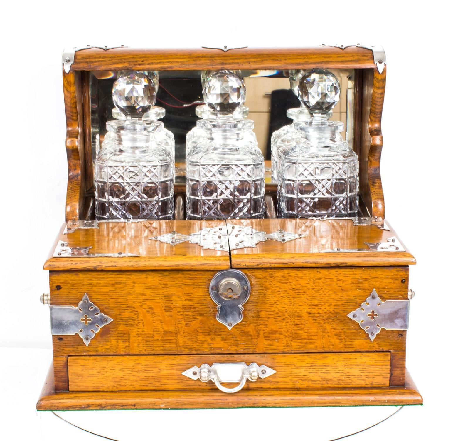 This is a superb antique Victorian oak cased three decanter tantalus with decorative cut brass silver plated mounts, circa 1880 in date.

It was skillfully crafted in tiger oak with beautiful silver plated mounts and stylish handles. There are