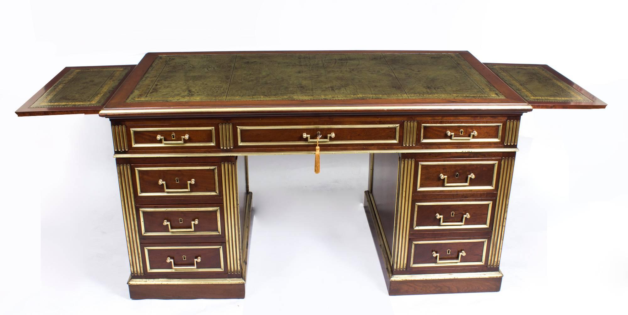 This is a beautiful antique French Empie Revival mahogany pedestal desk with stunning hand-hammered brass decoration, circa 1880 in date.

The rectangular top with an inset green and gold tooled leather writing surface, with three capacious frieze