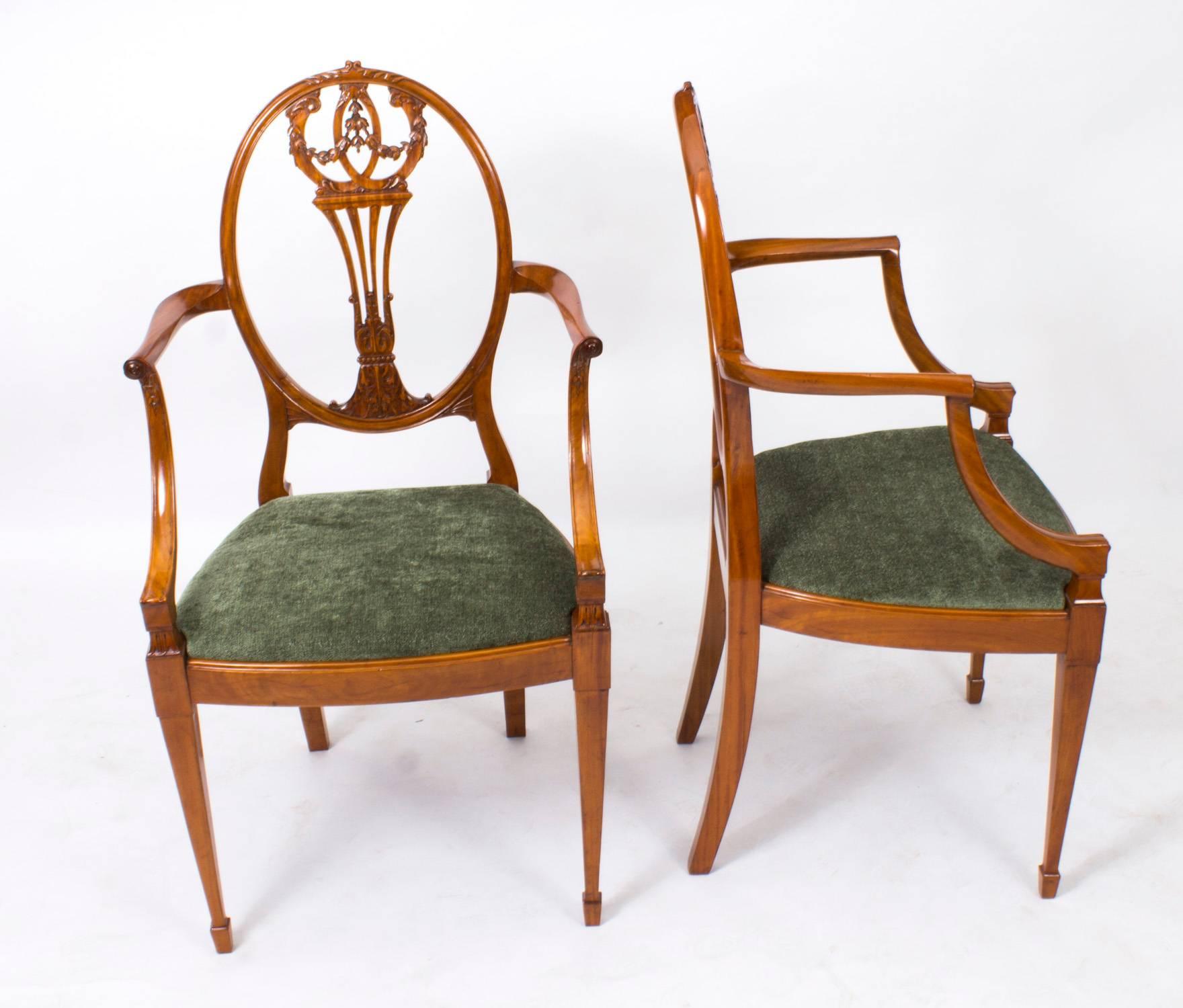 This is a fantastic antique pair of English Victorian Sheraton Revival satinwood armchairs, circa 1870 in date.

They are both expertly carved out of solid satinwood, each with Federal oval shield shaped central cartouches, decorated with ribbon