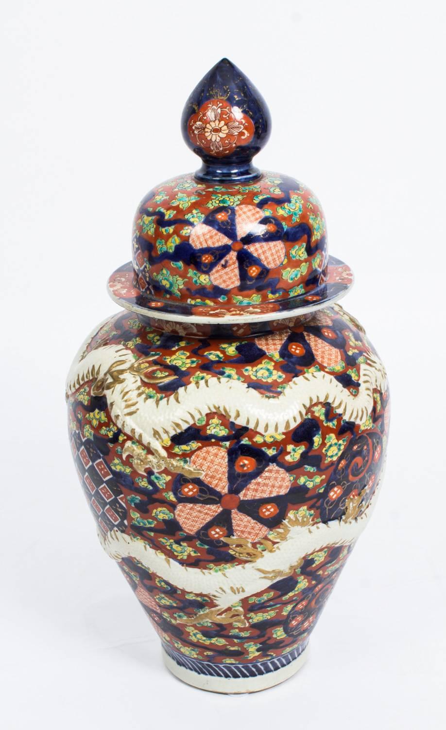 This is a lovely pair of Japanese Imari temple jars with lids, circa 1870 in date.

They feature a dense unusually decorated fan pattern design with two overlaid relief dragons to each and the traditional Imari color scheme of red, green, blue