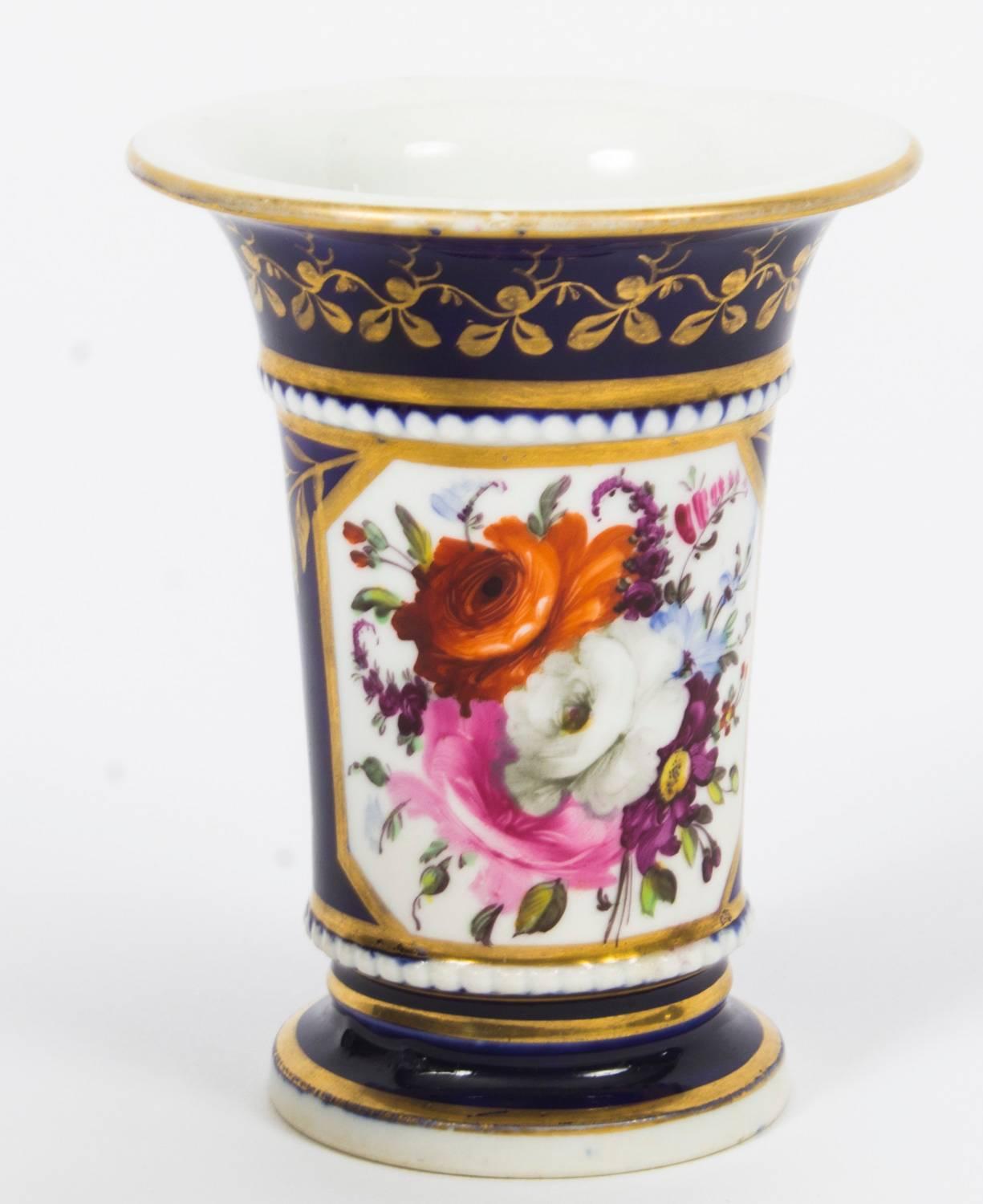 This is a truly superb pair of hand painted Regency English porcelain spill vases, Circa 1820 in date.

Beautifully hand painted with oval shaped panels of flowers on a Royal Blue ground with exquisite gilded decoration.

Instill the refined