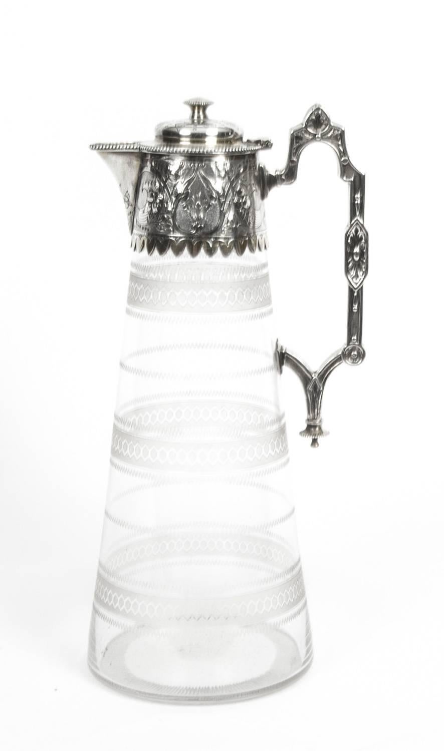 This is a wonderful Antique English Victorian silver plated and engraved crystal claret jug, circa 1870 in date.

It has a beautiful hand-chased mount with foliate decoration, a hinged domed lid with a cast finial, a scrolled cast handle, gilded