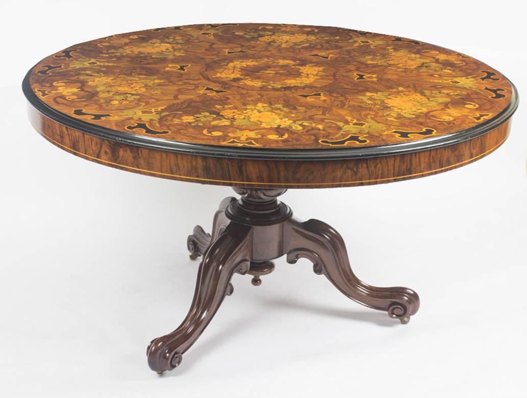 This is an elegant and rare English antique Victorian marquetry centre table, circa 1860 in date.

The burr walnut circular table features fine marquetry foliate and floral ornamentation with ebonised highlights and sits on a hand carved solid
