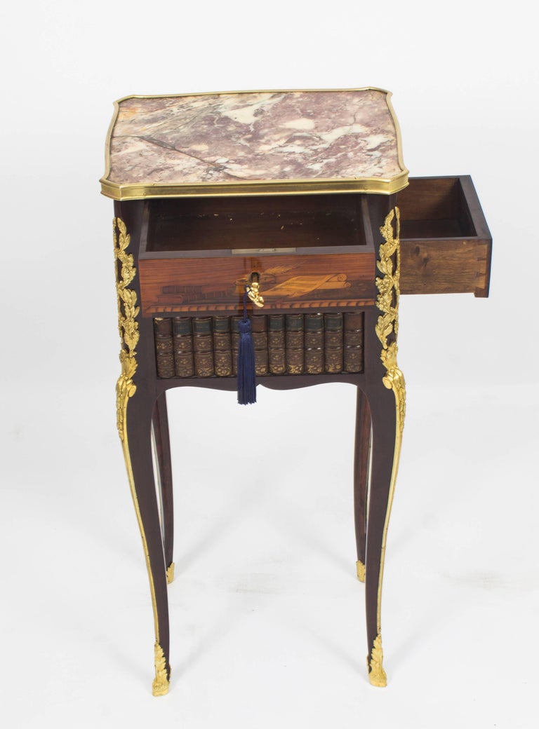A wonderful antique museum quality French Napoleon III bedside cabinet, circa 1860 in date.

The gilt bronze mounted kingwood, amaranth and marquetry table en chiffoniere has an inset marble top above a frieze drawer inlaid with quill, inkpot and