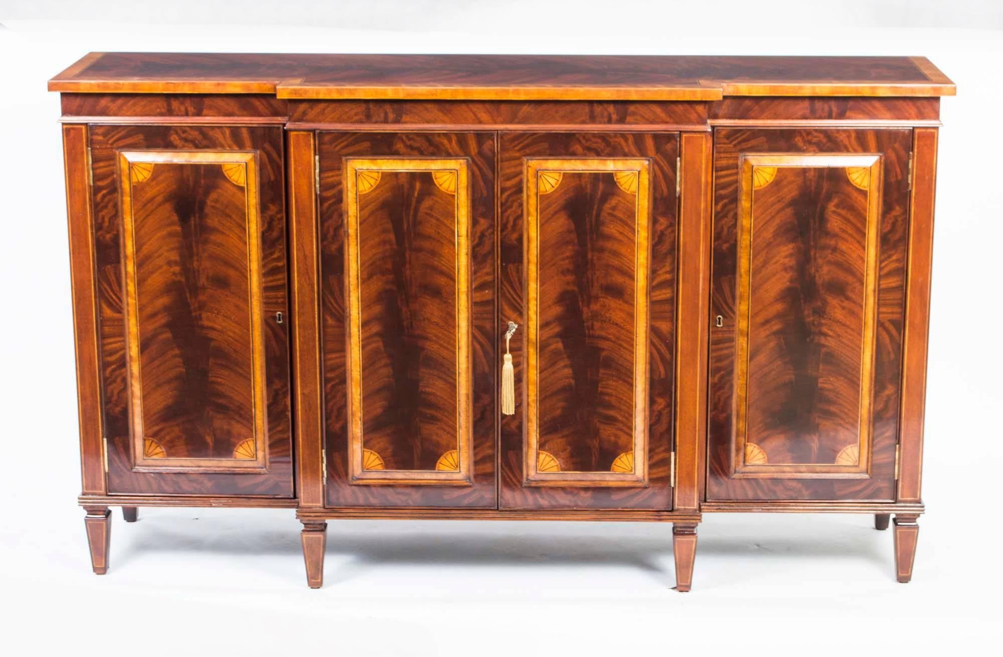 This is a beautiful breakfront flame mahogany sideboard with room for all your plates, china, glassware and cutlery, dating from the last quarter of the 20th century.

It has four doors and fabulous inlaid satinwood decoration of fans, inlay and