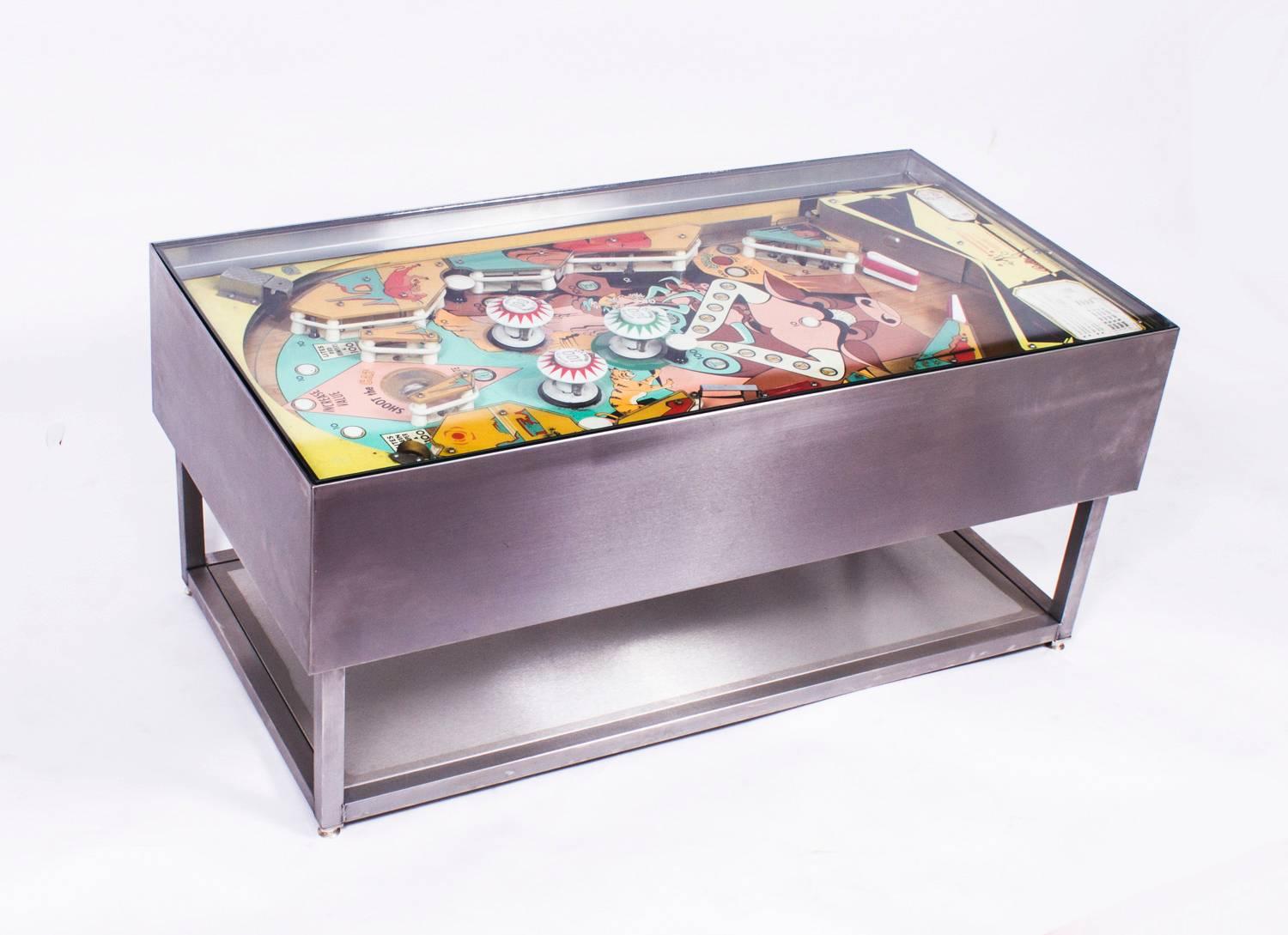 This is an original Trail Drive pinball machine that was cleverly converted into a coffee table, the pinball components are circa 1970 in age.

The colorful coffee table is made of brushed steel with a glass top. The internal components light up