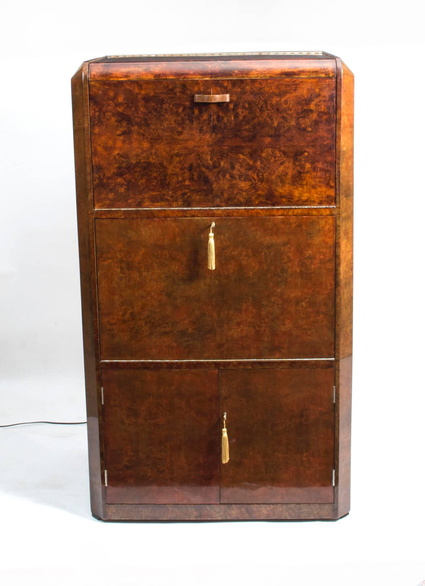 This is a fantastic antique Art Deco burr walnut cocktail cabinet, circa 1930 in date.

The hinged top opens to reveal a bleached interior with mirrored back and clear perspex glass and bottle holder.

This is a fall front central section to hold
