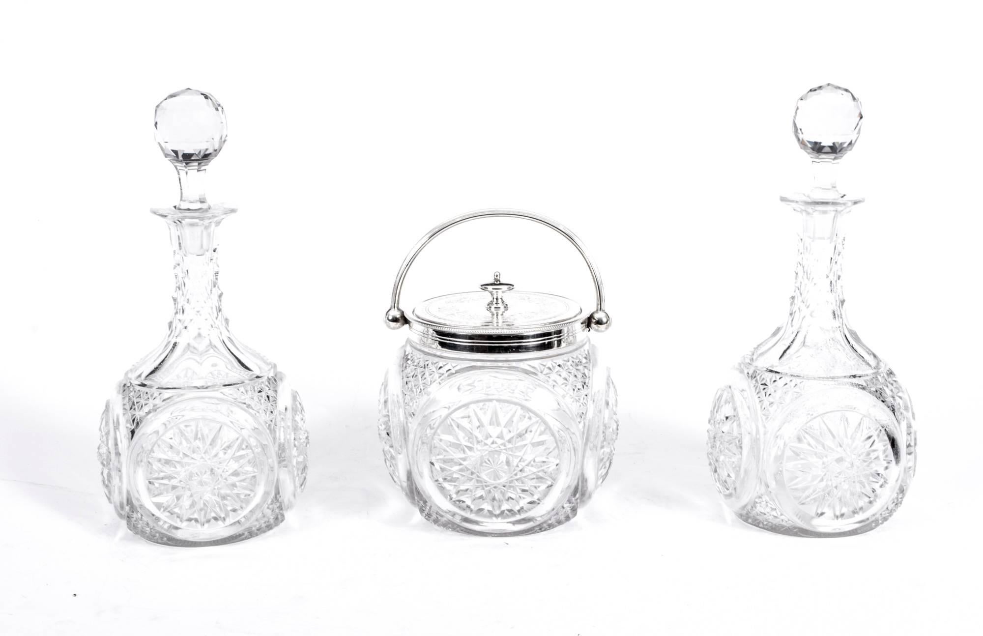 This is an attractive silver plated tantalus with two cut-glass decanters and a cut-glass and silver plate ice bucket in the Classic English style, circa 1880 in date.

It bears the makers mark GCW for G.C.Whiles of Birmingham England.

The