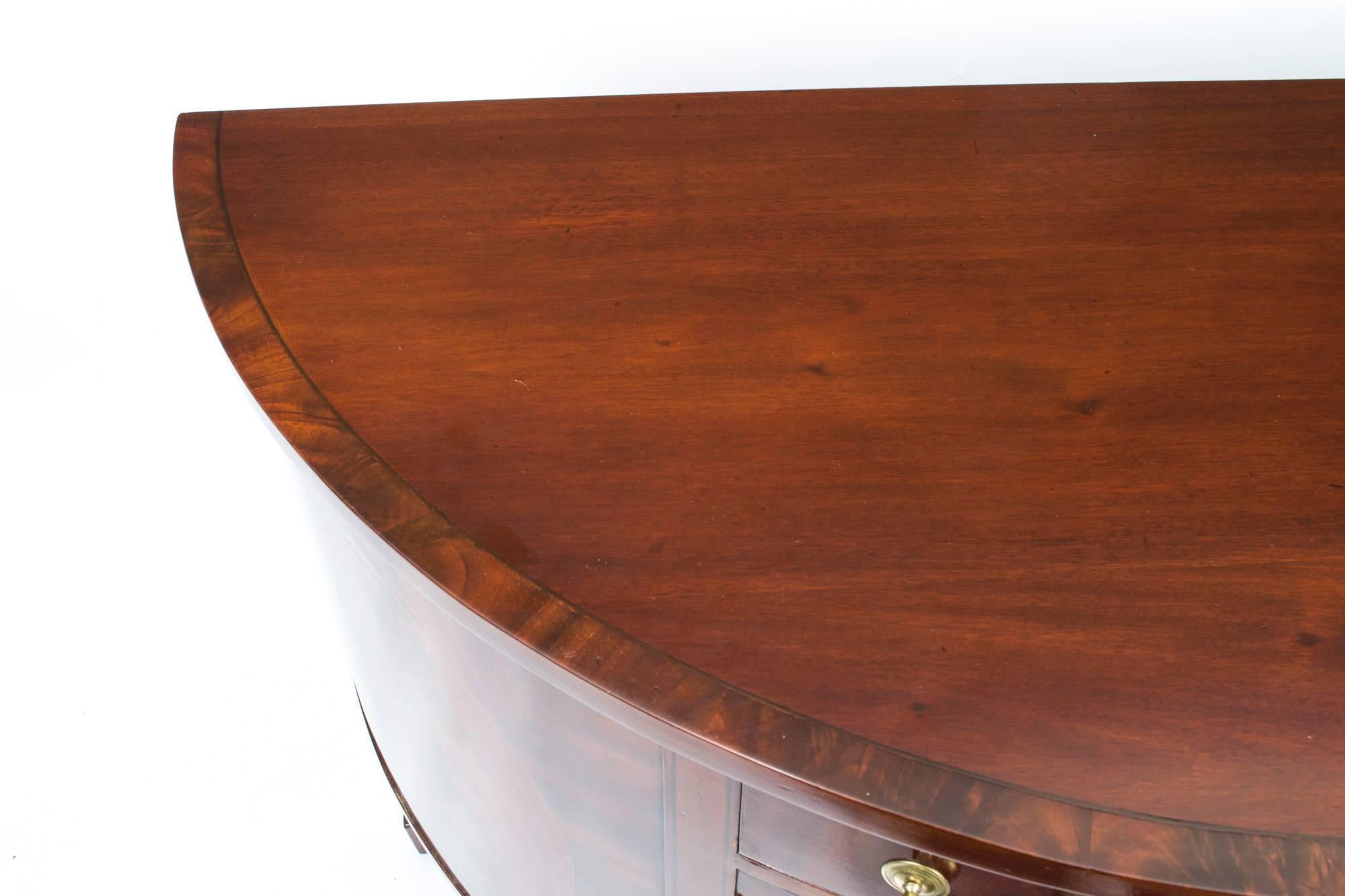 This is a superb antique George III period demilune flame mahogany side cabinet circa 1780 in date.

The half-moon top is beautifully crossbanded in rosewood above a capacious central drawer in the frieze. There are two cupboard doors below with a