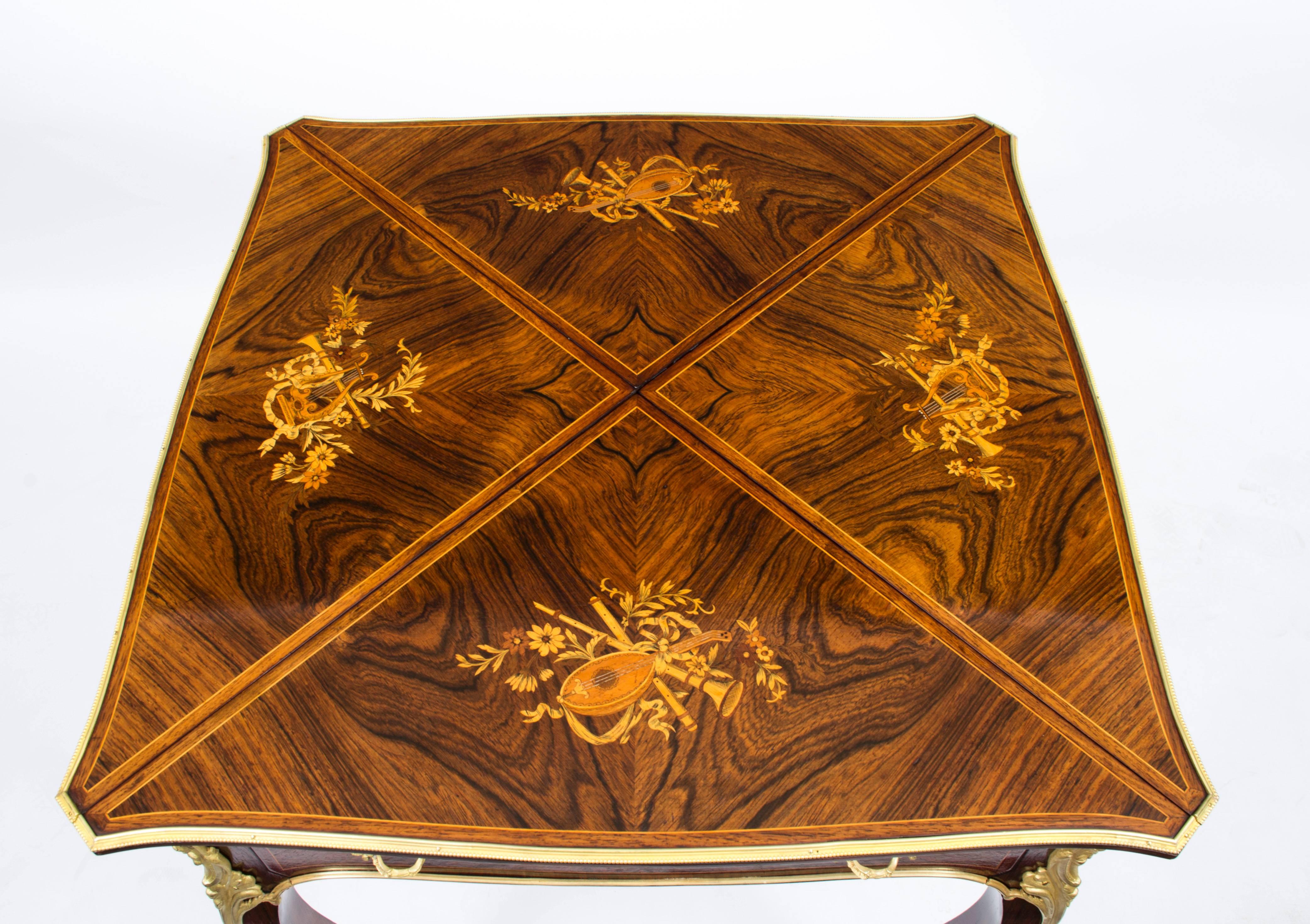 This is a beautiful antique Victorian rosewood and ormolu mounted envelope card table, circa 1880 in date.

The card table is made from superb quality rosewood, has the most striking musical instrument inlay on each leaf and superb gilded ormolu