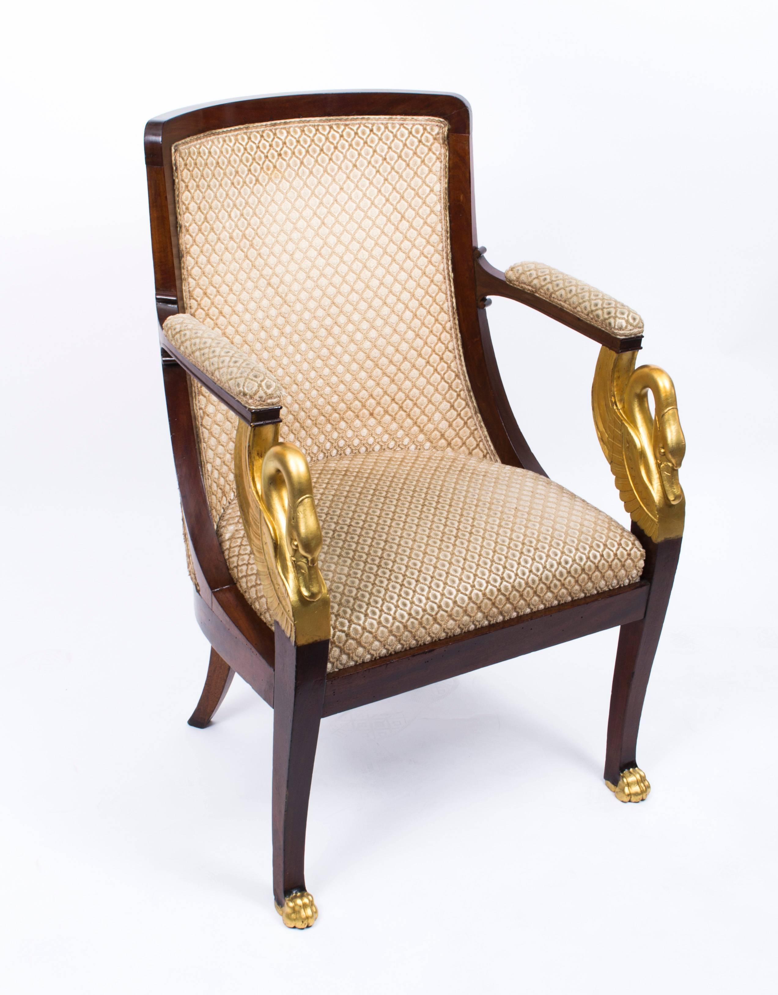 This is a beautiful pair of hand-carved and gilded solid mahogany French Empire armchairs circa 1820 in date.

They have beautifully carved and gilded swan neck decoration and front legs that terminate in decorative gilded paw feet.

They are