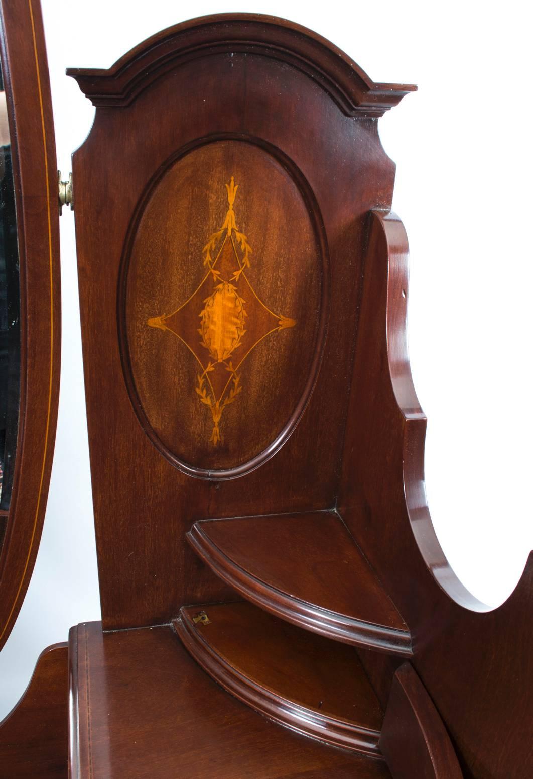 This is a totally fabulous antique inlaid mahogany dressing table with adjustable mirror, circa 1900 in date.

The dressing table has a raised back with a diamond shaped and laurel wreath medallion satinwood inlay to either side of an oval swing