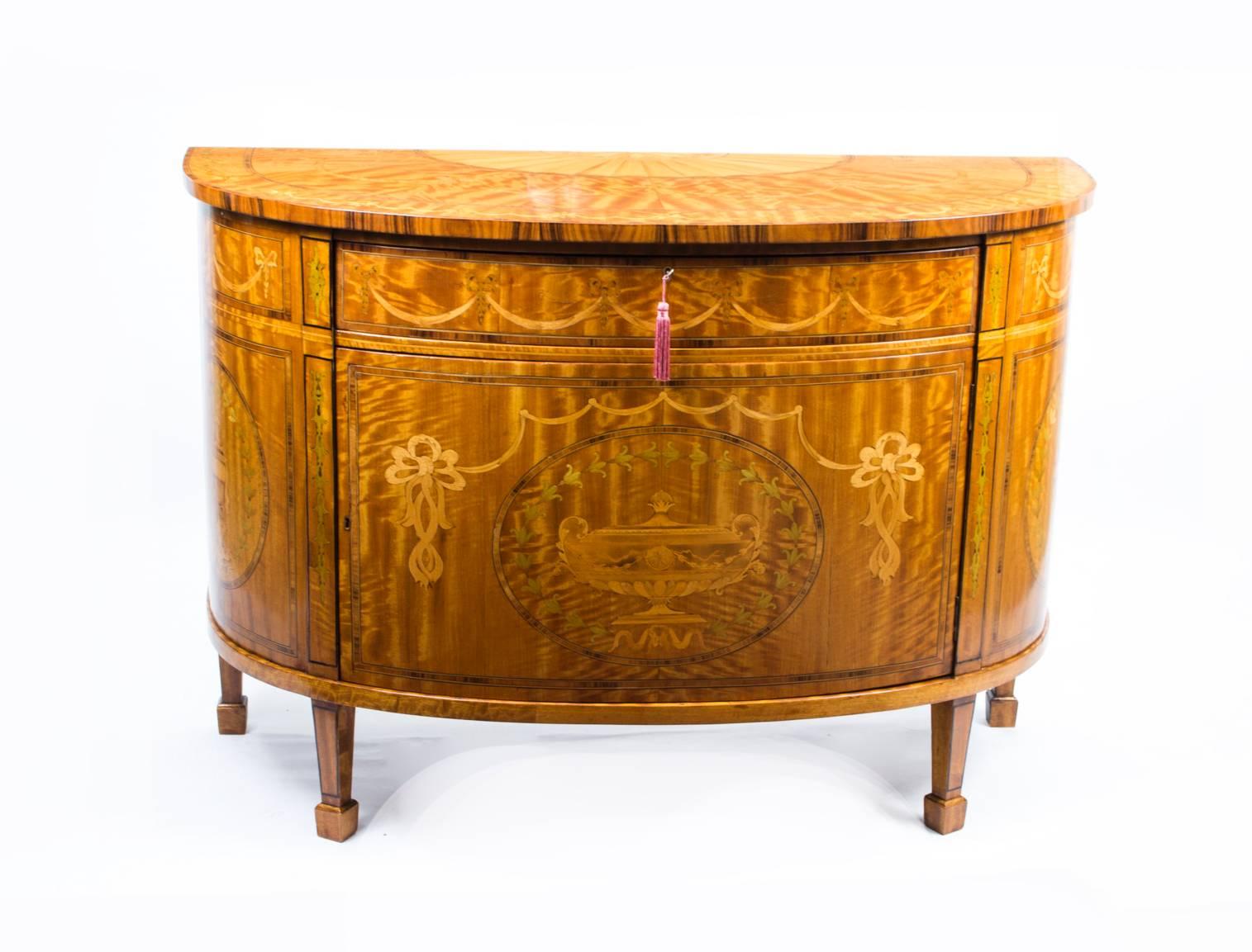 This is a gorgeous pair of George III style satinwood demilune commodes with fruitwood inlaid marquetry decoration, early 20th century in date.

Each chest has striking Santos rosewood crossbanding with a decorative shell rosette within a fan