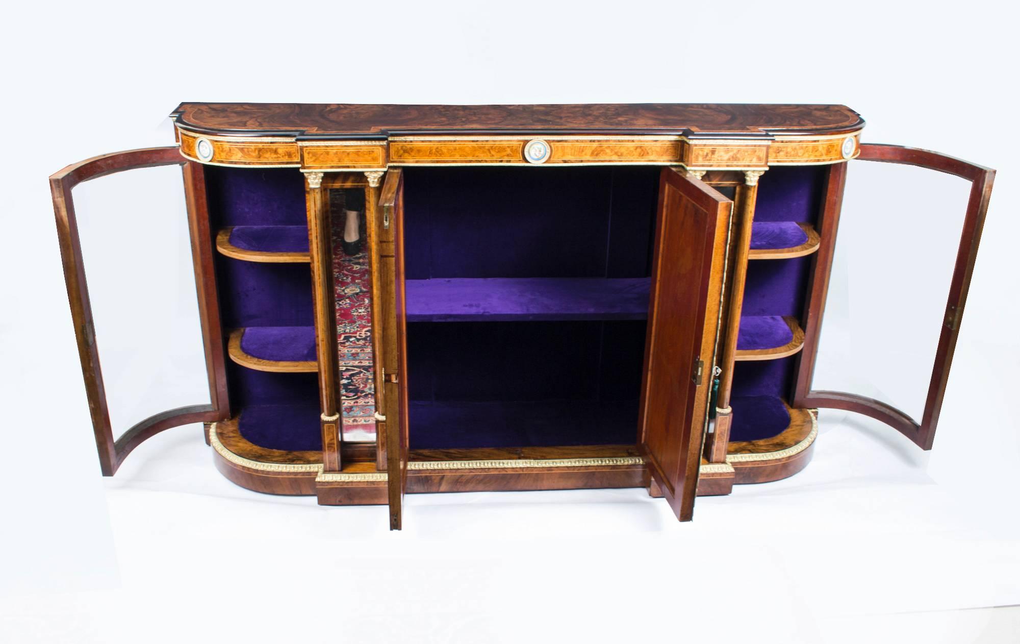 This is a superb antique Victorian burr walnut, ebonized, Sevres porcelain and ormolu-mounted credenza, circa 1860 in date.

It has a shaped bow front above a central pair of doors that are mounted with beautiful oval hand painted porcelain Sevres