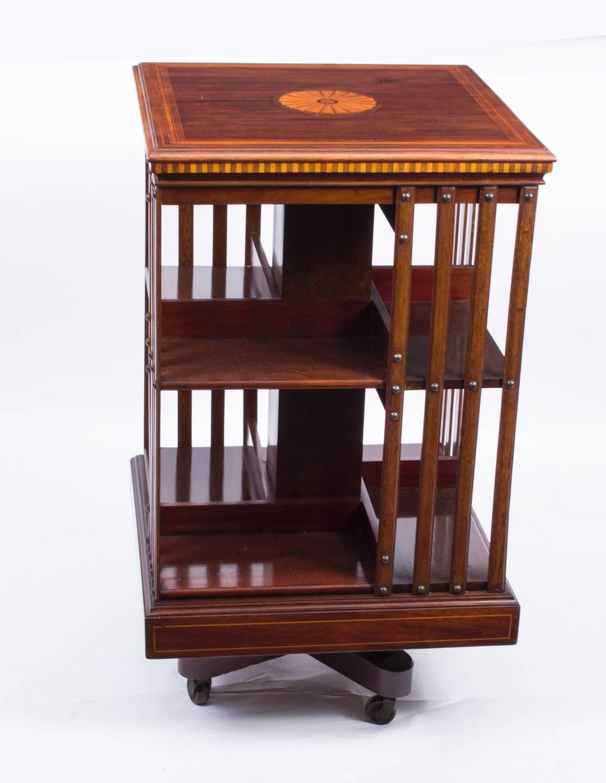 This an exquisite antique revolving bookcase bearing the ivorine plaque of the renowned Victorian retailer and manufacturer Maple & Co, circa 1900 in date.

It is made of mahogany, revolves on a solid cast iron base, has inlaid boxwood lines to