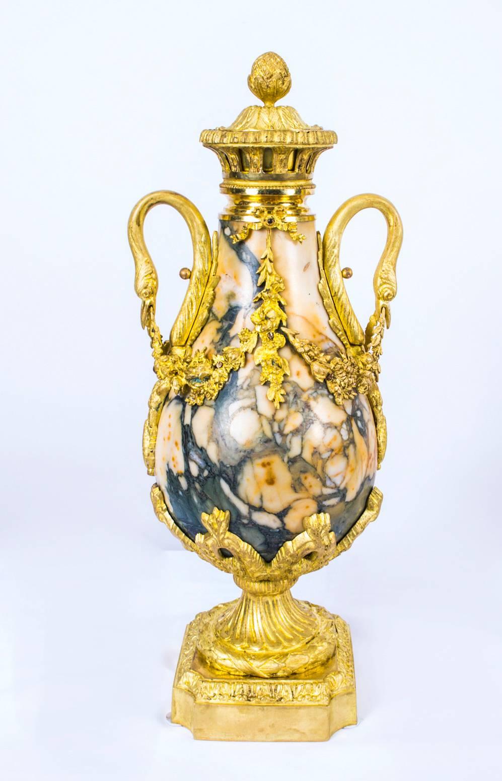 This is a magnificent antique pair of French figured Carrara marble and gilded bronze urns in the Louis XV manner and dating from circa 1870.

The urns feature gilt bronze gadrooned covers with acorn finials on pierced reeded necks. The pair of swan