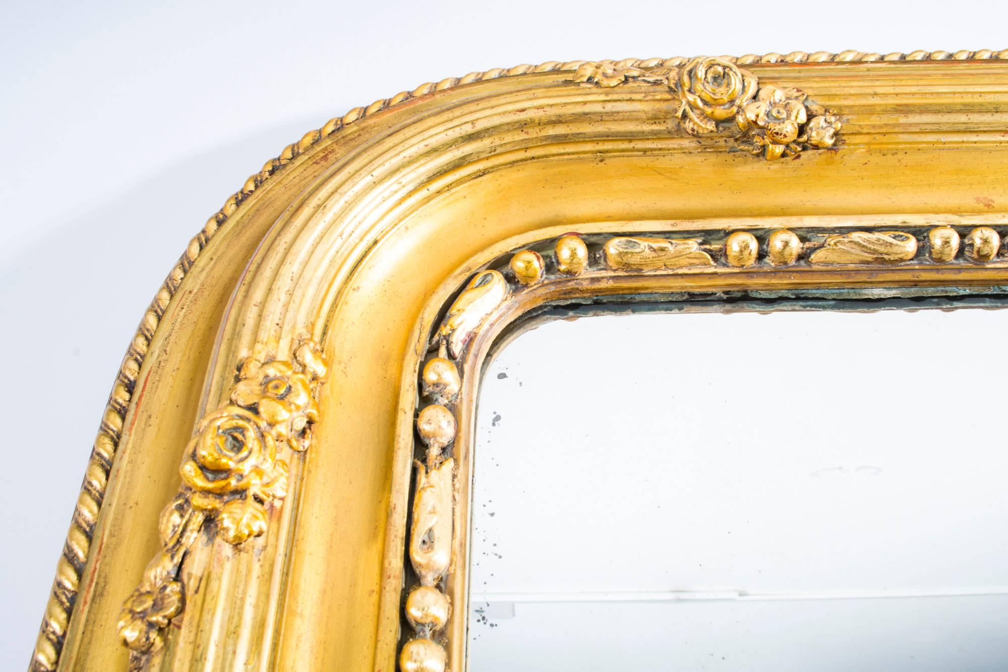 An large and impressive French carved giltwood and gesso overmantel mirror, circa 1860 in date.
The rectangular mirror has its original glass plate. It features a superbly carved giltwood and gesso frame which is decorated with a central fluted