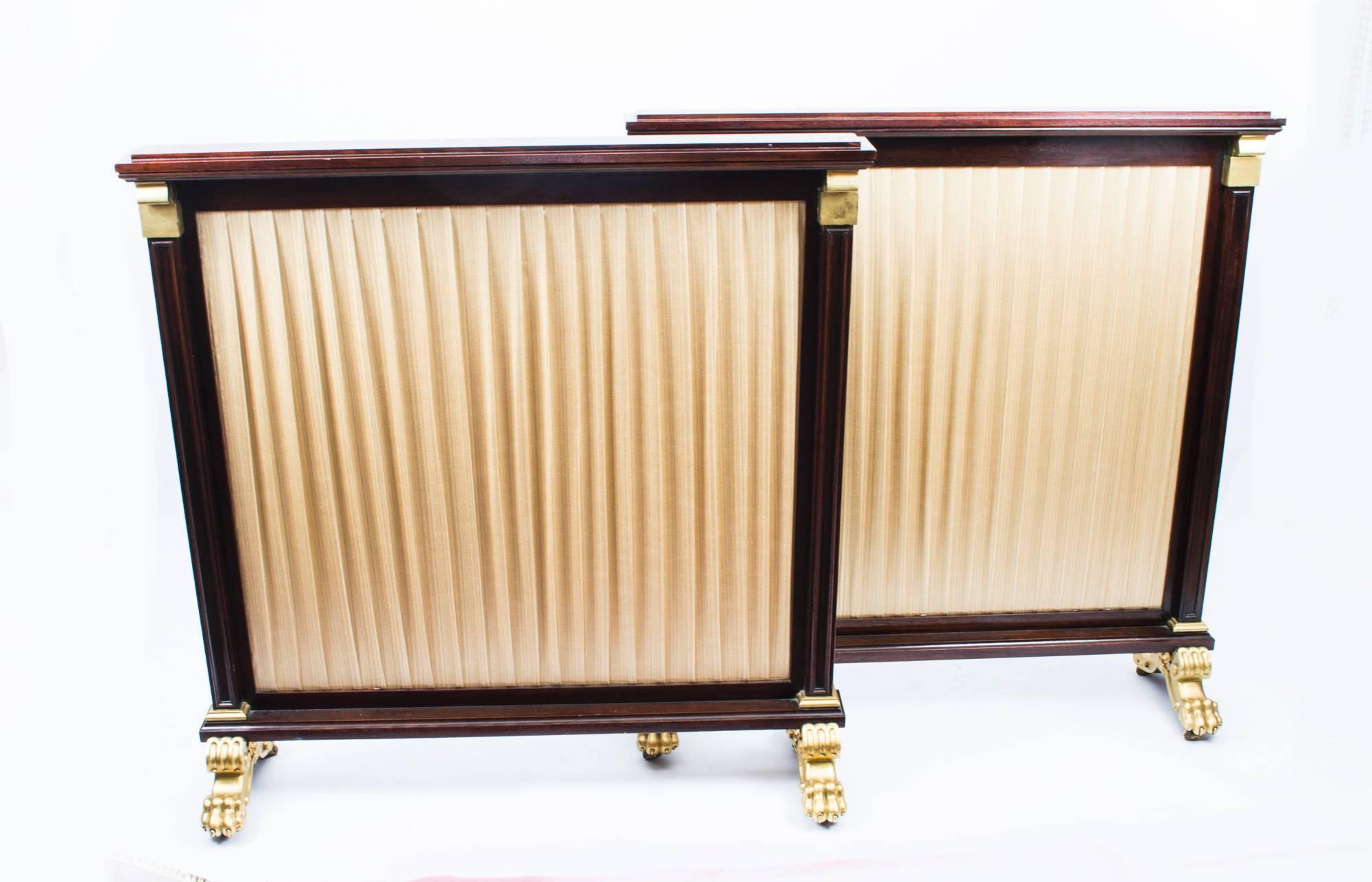 An elegant pair of William IV mahogany and gilded fire screens, circa 1835 in date.

Each features a pleated golden silk covered panel with mahogany back. They are each raised on a pair of twin gilded lion's paw feet, with gilded shell mounts. The