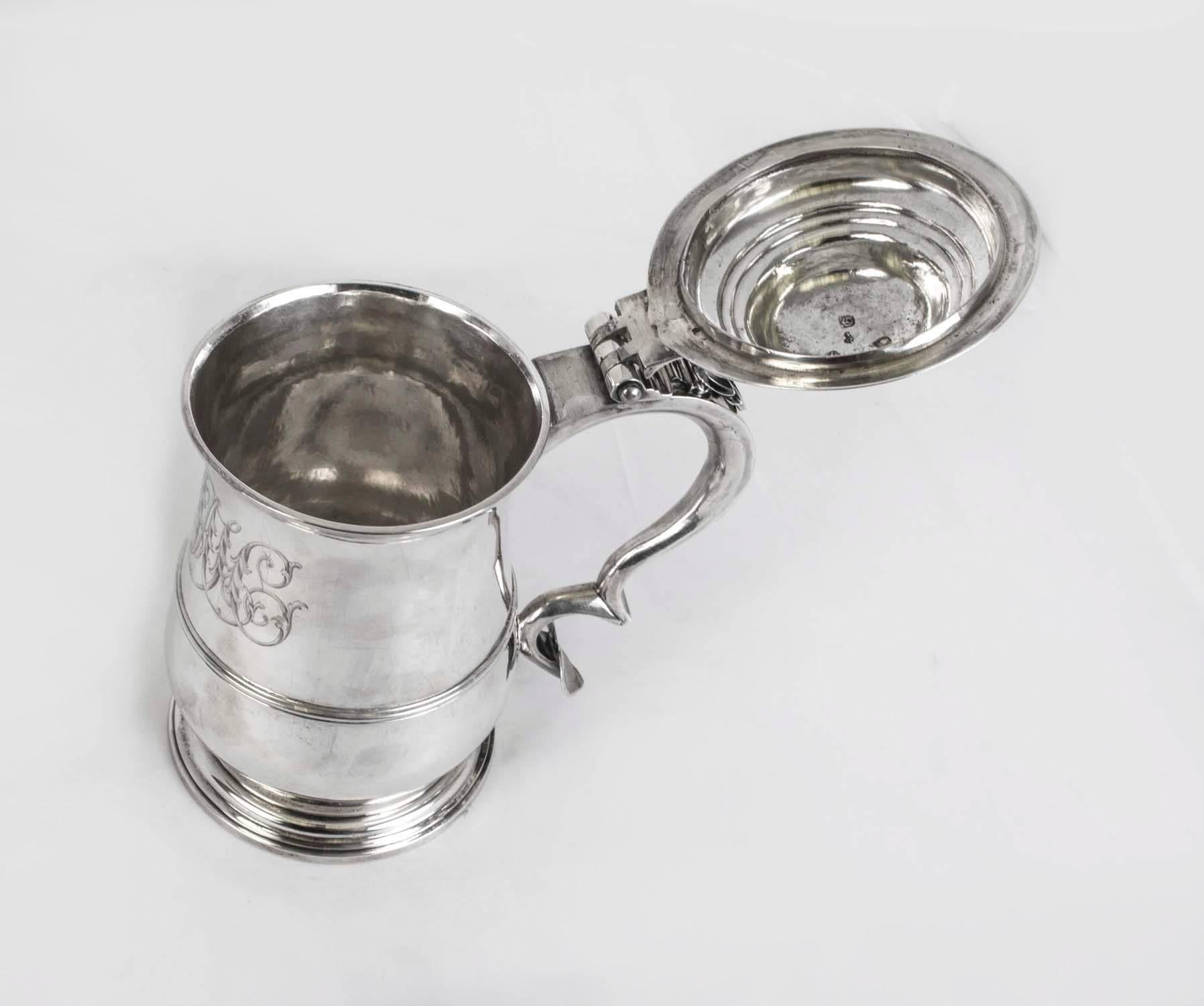 This is a wonderful large antique English George III silver cylindrical tankard with hallmarks for London, 1762 and the makers mark of W & R Peaston.

The tankard has a hinged raised cover with scroll thumb piece, it has a bold scroll handle