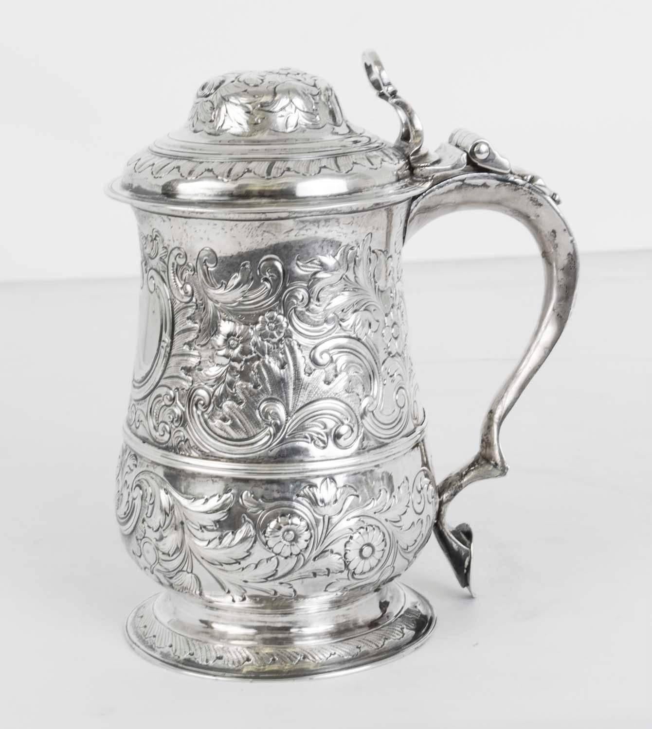 This is a wonderful antique English George III silver lidded tankard with hallmarks for London, 1773 and the makers mark of the renowned silversmiths John King.

The tankard has wonderful embossed floral decorations throughout with a blank