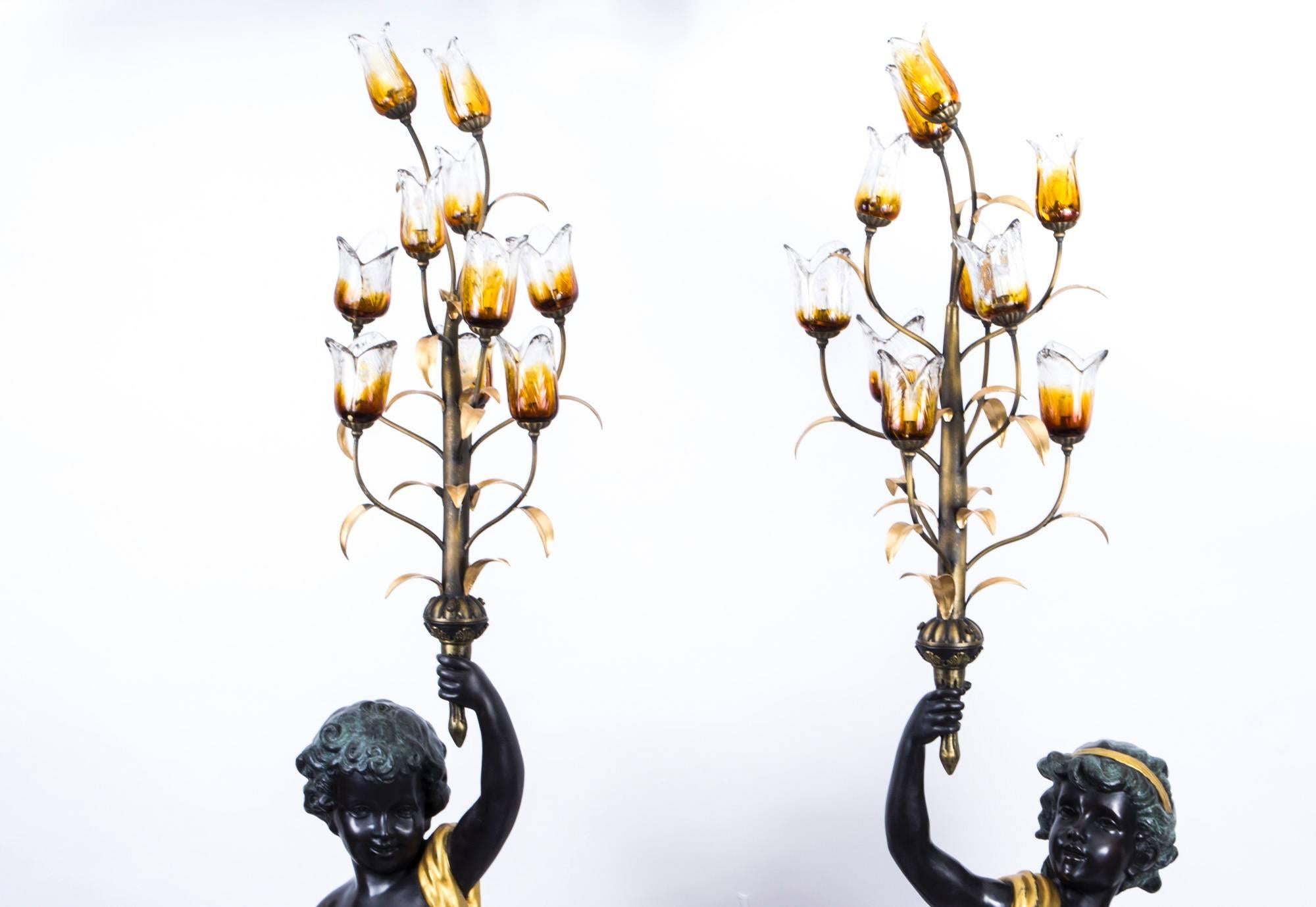 This is a superb pair of gilded bronze ten light candelabra set on cylindrical fluted black and brown solid marble bases, dating from the last quarter of the 20th century.

The candelabra feature a pair of green and black patinated putti who are